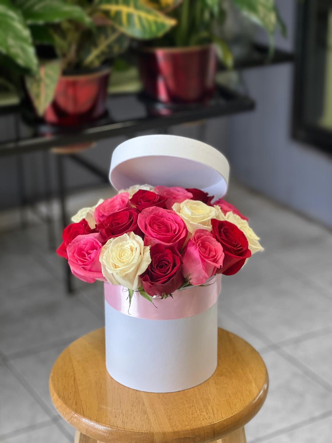 Pink, red, and white roses arranged in a round hat box