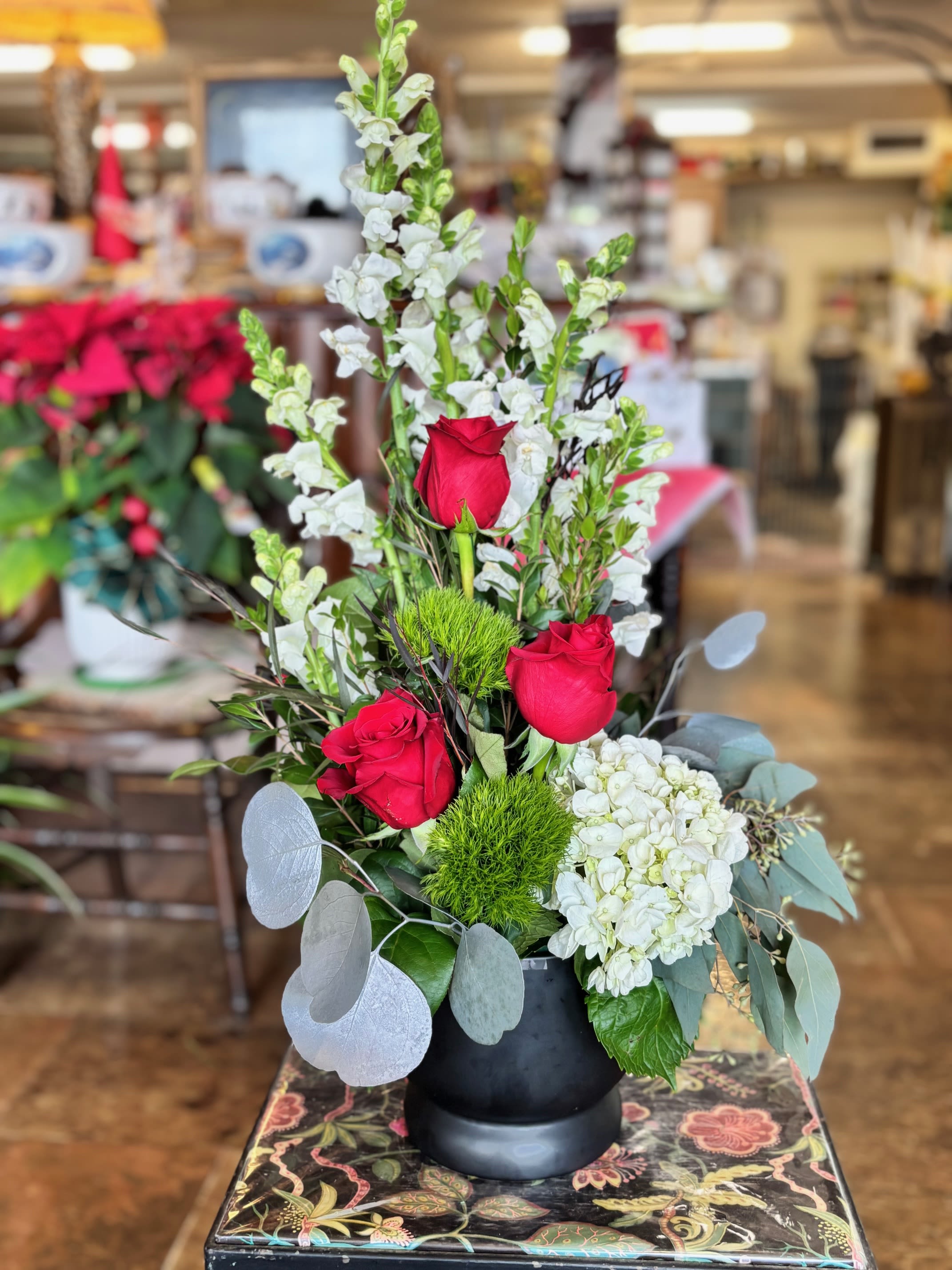 Red roses and white flowers arranged in a black vase