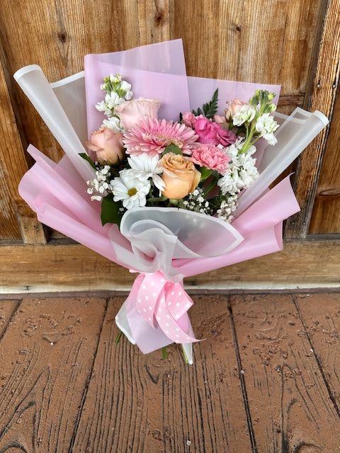 Pink and peach mixed bouquet wrapped in pastel paper with a ribbon