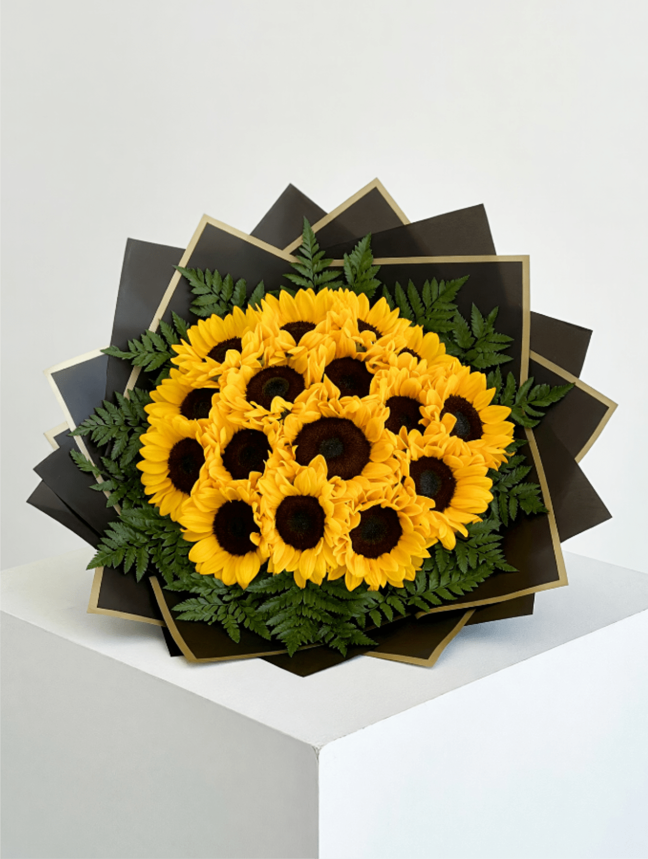 Bouquet of yellow sunflowers with dark centers and fern accents