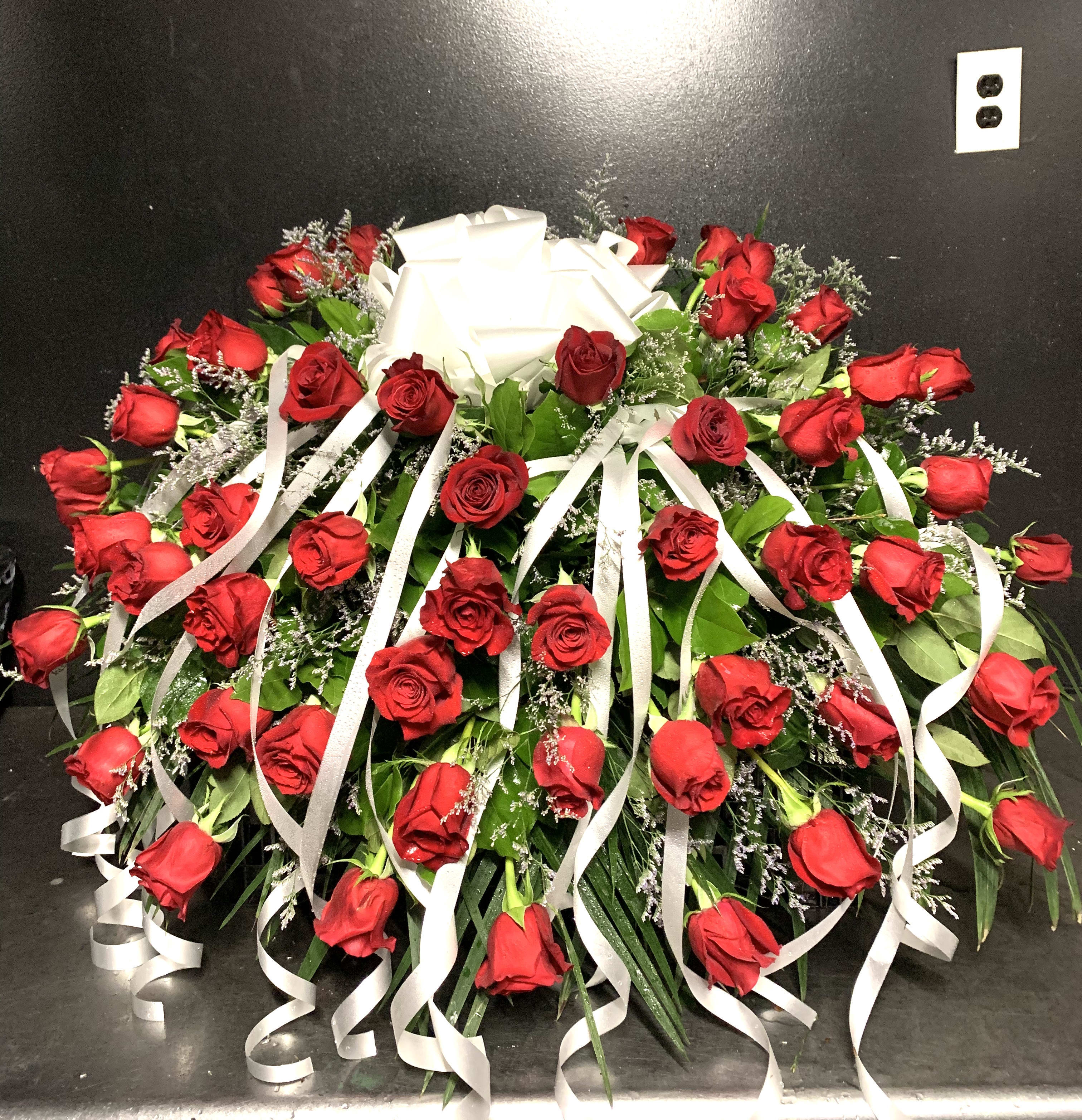 Large arrangement of red roses with white ribbon streamers and a bow