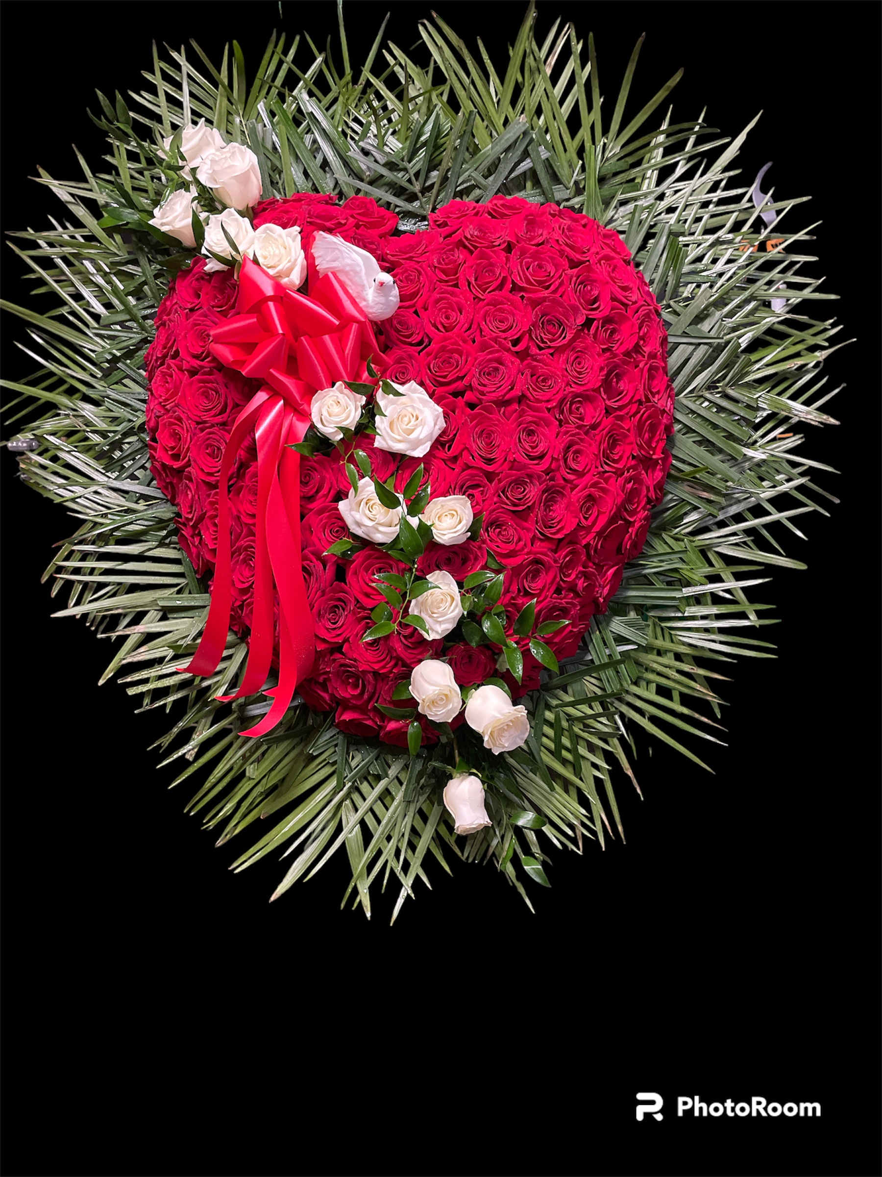 Heart-shaped red rose arrangement with white roses and a red ribbon