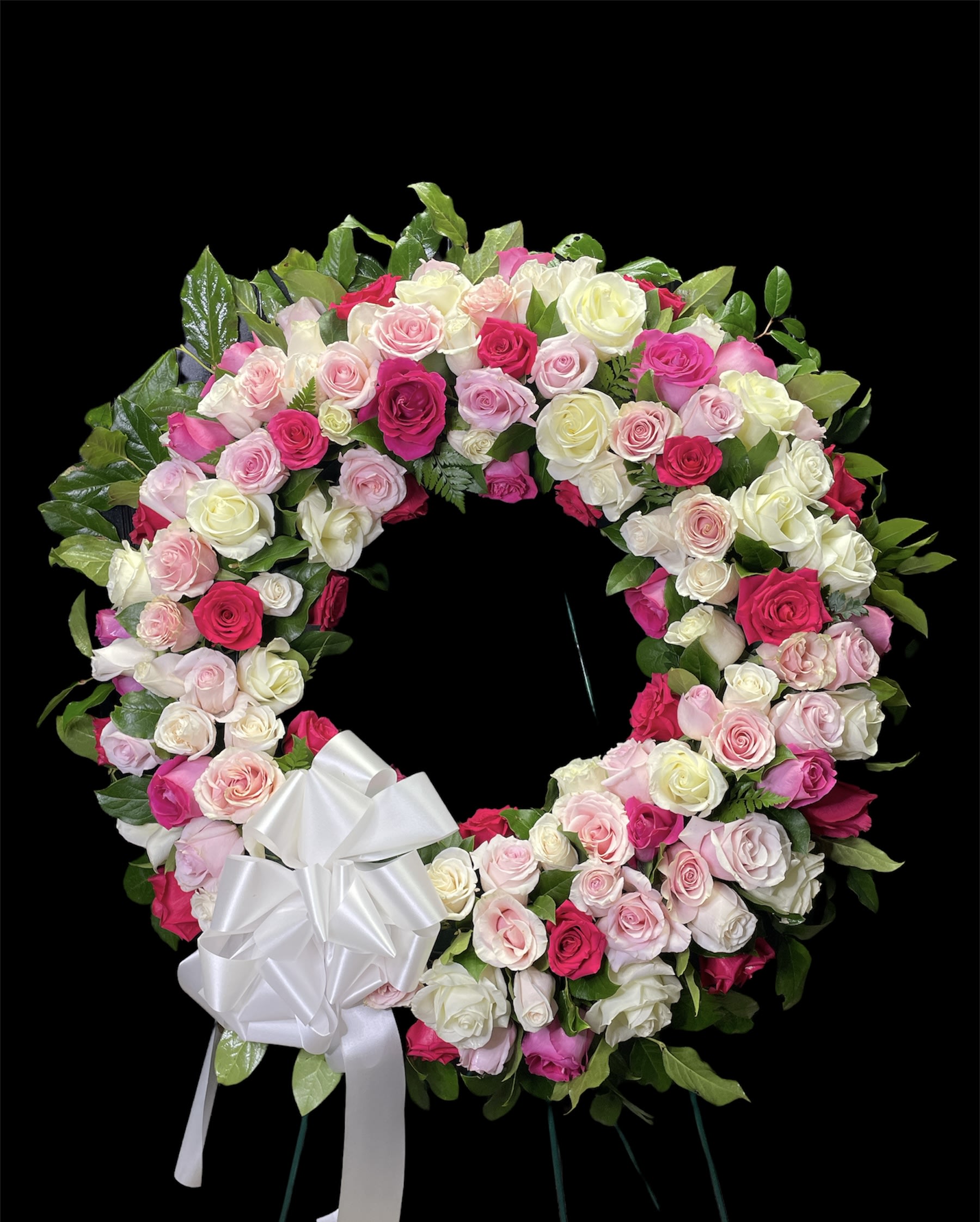 Heart-shaped wreath of pink and white roses with a white bow