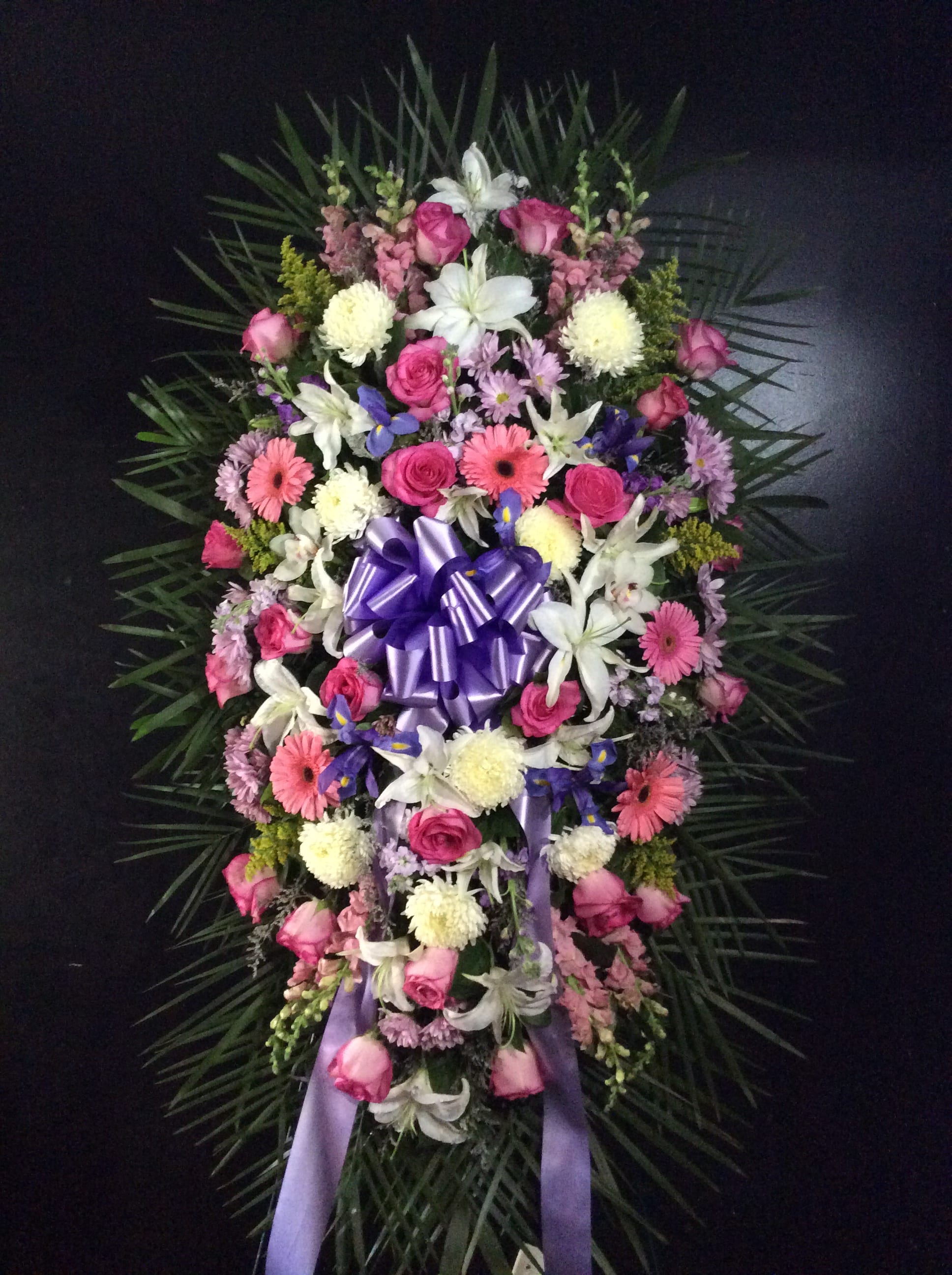 Standing floral spray with pink and white flowers and a purple ribbon bow