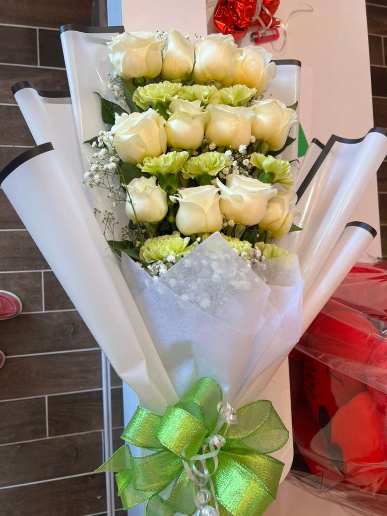 Bouquet of white roses and pale green carnations wrapped in white paper