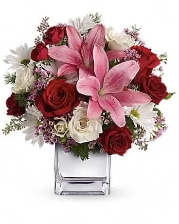 Happy in Love Bouquet - The beauty of red roses, the fragrance of pink lilies beautifully presented in a sparkling mirrored silver cube. Bouquets this outrageously romantic are what Valentine's Day is all about. She'll be thrilled. Totally thrilled. This knockout bouquet includes red roses, red spray roses, white spray roses, pink asiatic lilies, white daisy spray chrysanthemums and pink waxflower accented with ming fern and assorted greenery. Delivered in a mirrored silver cube. 