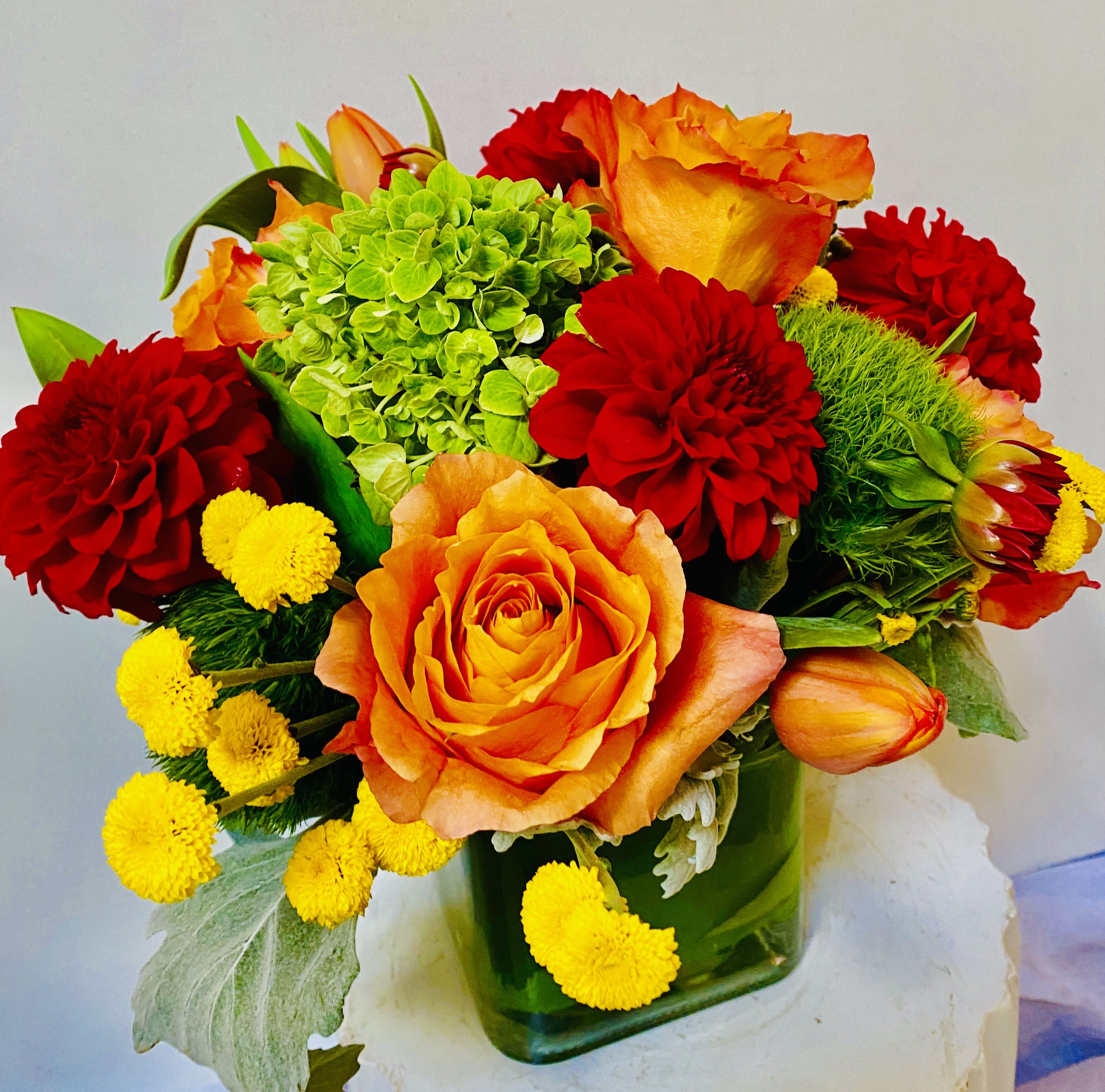 Bouquet of orange and red flowers in a green glass vase