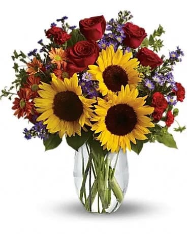 Pure Happiness - Pure happiness is what this pretty bouquet delivers - whether you're sending it for a fall birthday, Thanksgiving, thank you, or simply just because. Surely, no one can be in the presence of something so inherently happy and not smile. Sunny sunflowers, red roses and miniature carnations, bronze daisy spray chrysanthemums, large lavender monte cassino asters and autumn greens are beautifully arranged in a clear glass vase. 