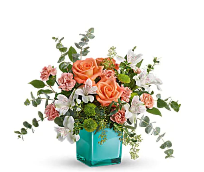 Sunset Splash Bouquet - Inspired by the warm peach skies and crystal blue waters of a tropical sunset, this fun-filled rose bouquet adds a splash of happiness to any occasion! This delightful arrangement features peach roses, white alstroemeria, peach miniature carnations, green button spray chrysanthemums, spiral eucalyptus, seeded eucalyptus, oregonia, and lemon leaf. Delivered in an Aqua Color Splash Cube.   Orientation : All-Around  All prices in USD ($)  Standard  TEV59-7A  Deluxe  TEV59-7B  Premium  TEV59-7C