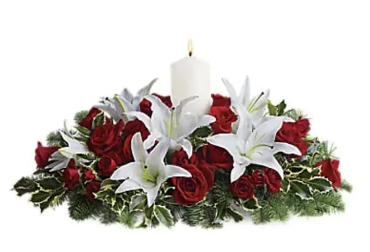 Luminous Lilies Centerpiece - This luminous centerpiece is a glowing way to spread the joy of the season. Whether displayed on the dining table or placed elsewhere, it will light up any room with holiday cheer. Gorgeous pure white asiatic lilies, radiant red roses, spray roses and pretty winter greens are arranged around an elegant white pillar candle. It's regal and radiant.   Orientation : All-Around  All prices in USD ($)  Standard  T128-3A  Deluxe  T128-3B  Premium  T128-3C