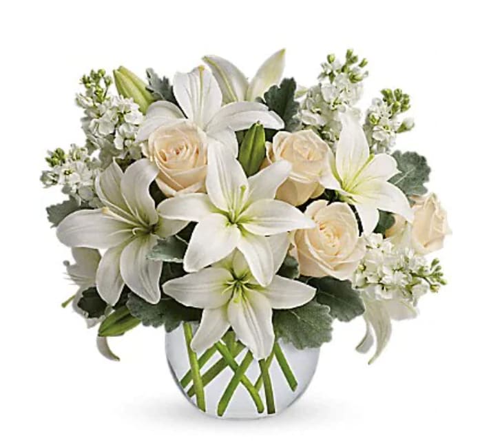 Isle Of White - Like a vacation for the senses, this lovely bouquet delivers an oasis of beauty and elegance. Soothing, serene and very special. Crème roses, white asiatic lilies and stock stem are incredibly arranged in a bubble vase. When it comes to bouquets, this is definitely the right way to do white.   Orientation : All-Around  All prices in USD ($)  Standard  T55-3A  Deluxe  T55-3B  Premium  T55-3C