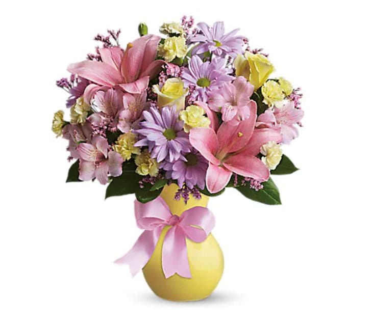 Pink and lavender mixed bouquet in a yellow vase with a pink ribbon