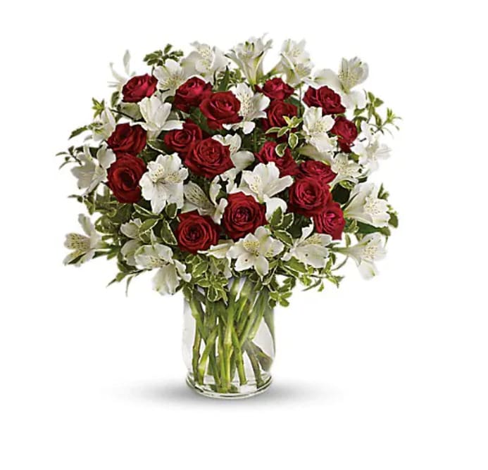 Red roses and white alstroemeria in a clear glass vase