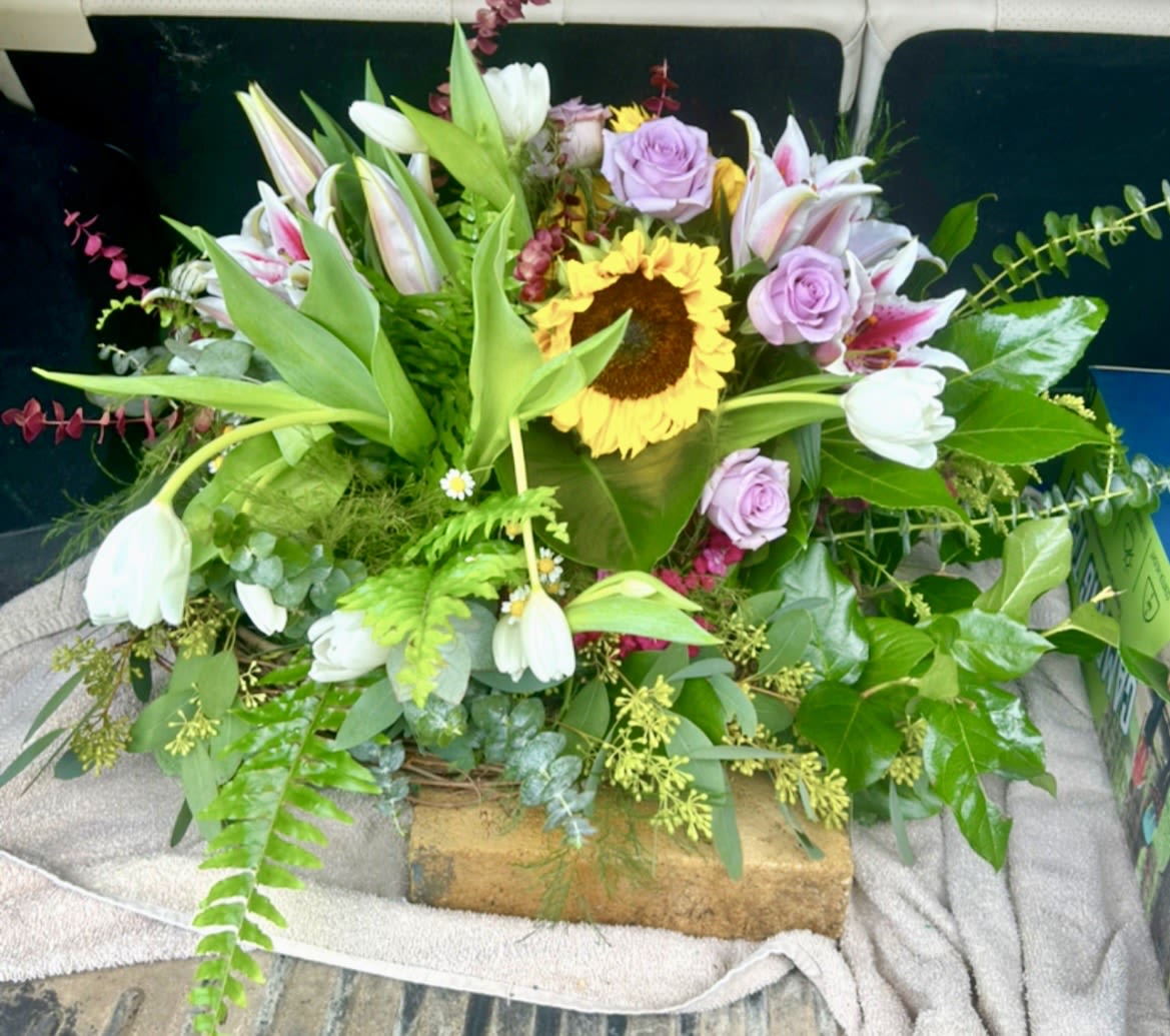 Lavender Meadow Luxe - A Custom Design by Wonderland Flowers - A lush garden-inspired arrangement featuring radiant sunflowers, lavender roses, fragrant stargazer lilies, tulips, and flowing seasonal greenery designed with organic movement and elegance.