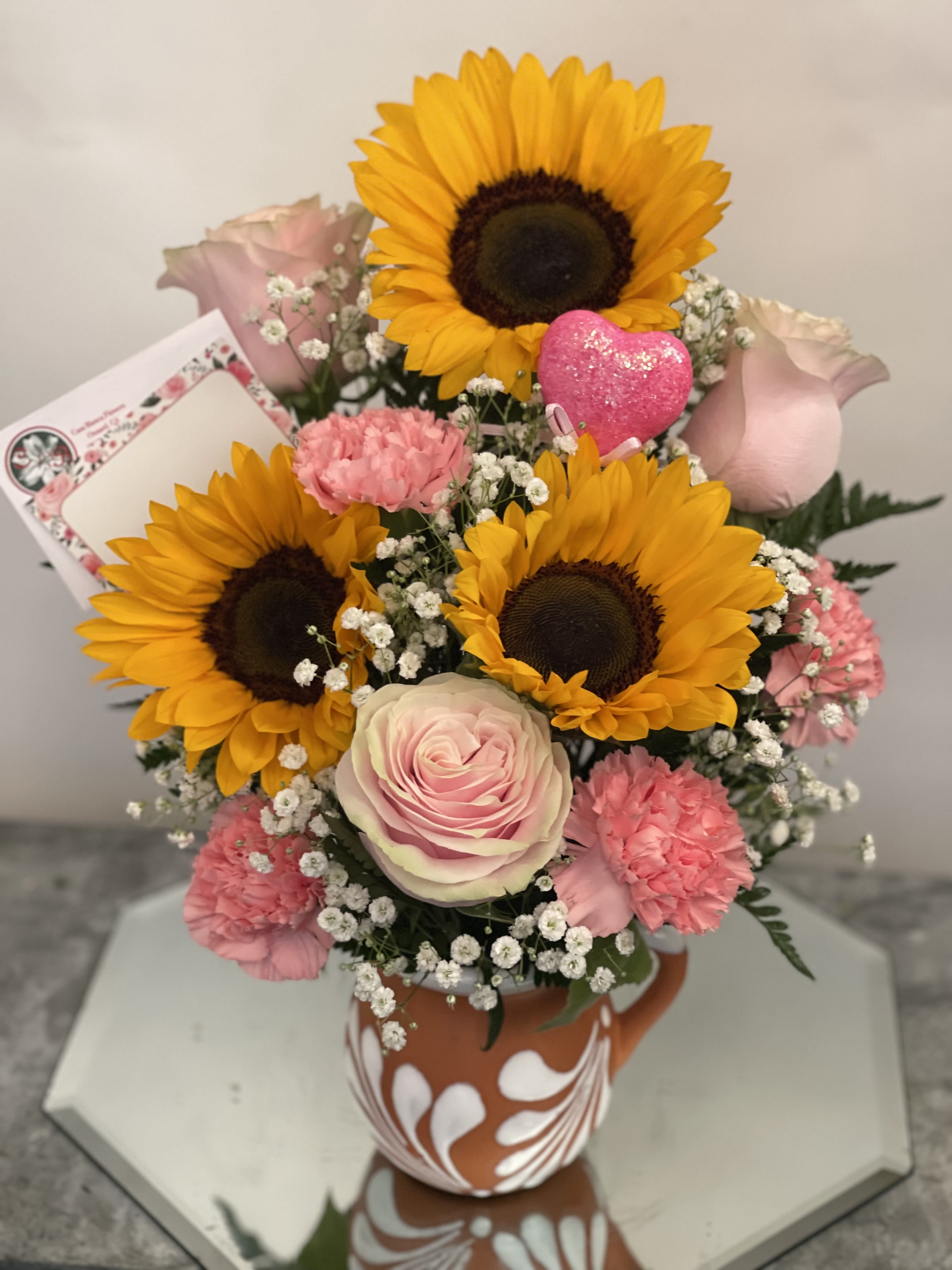 Bouquet of sunflowers, pink roses, and carnations in a patterned vase