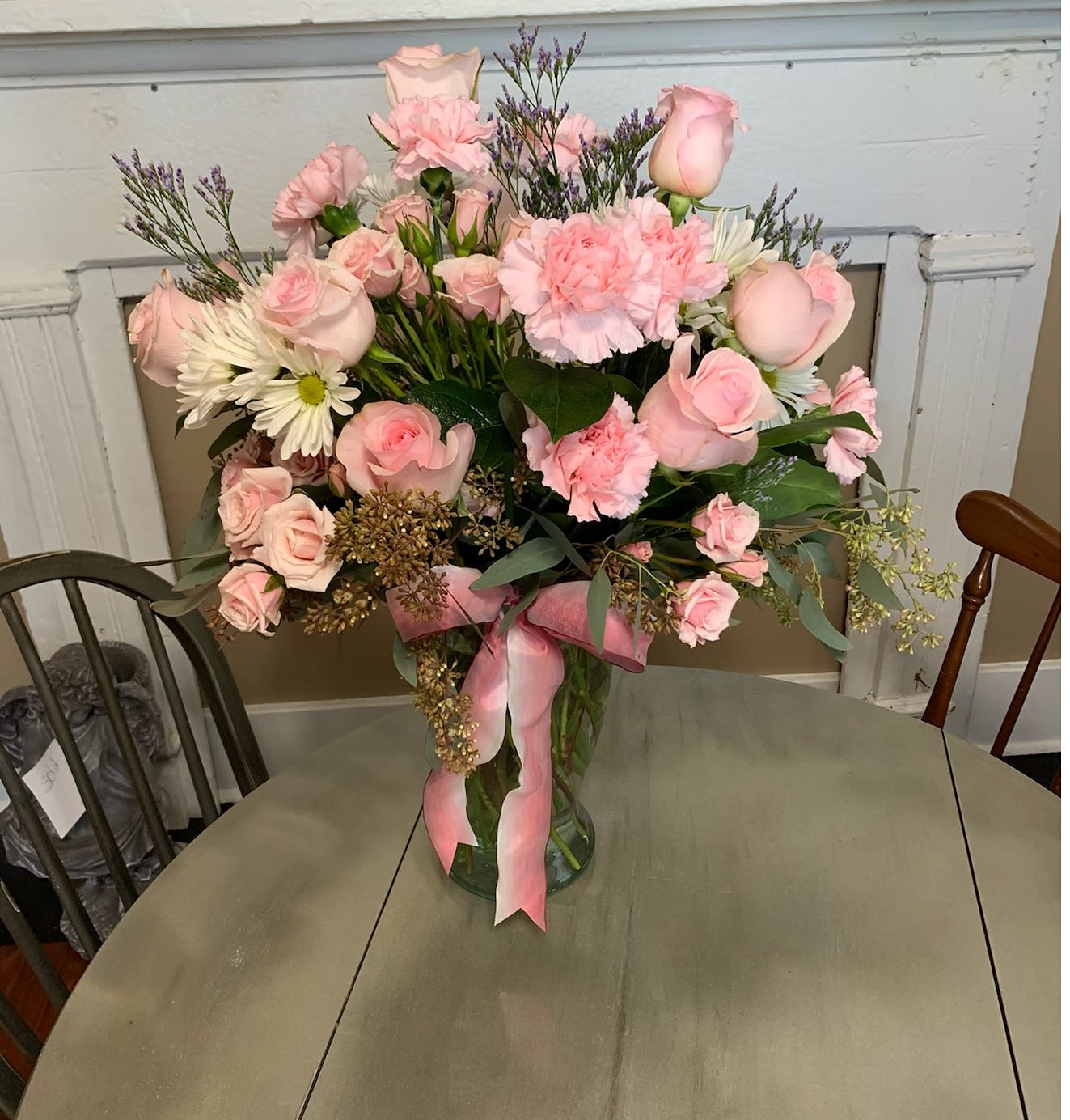 Pink roses and carnations in a glass vase with a pink ribbon