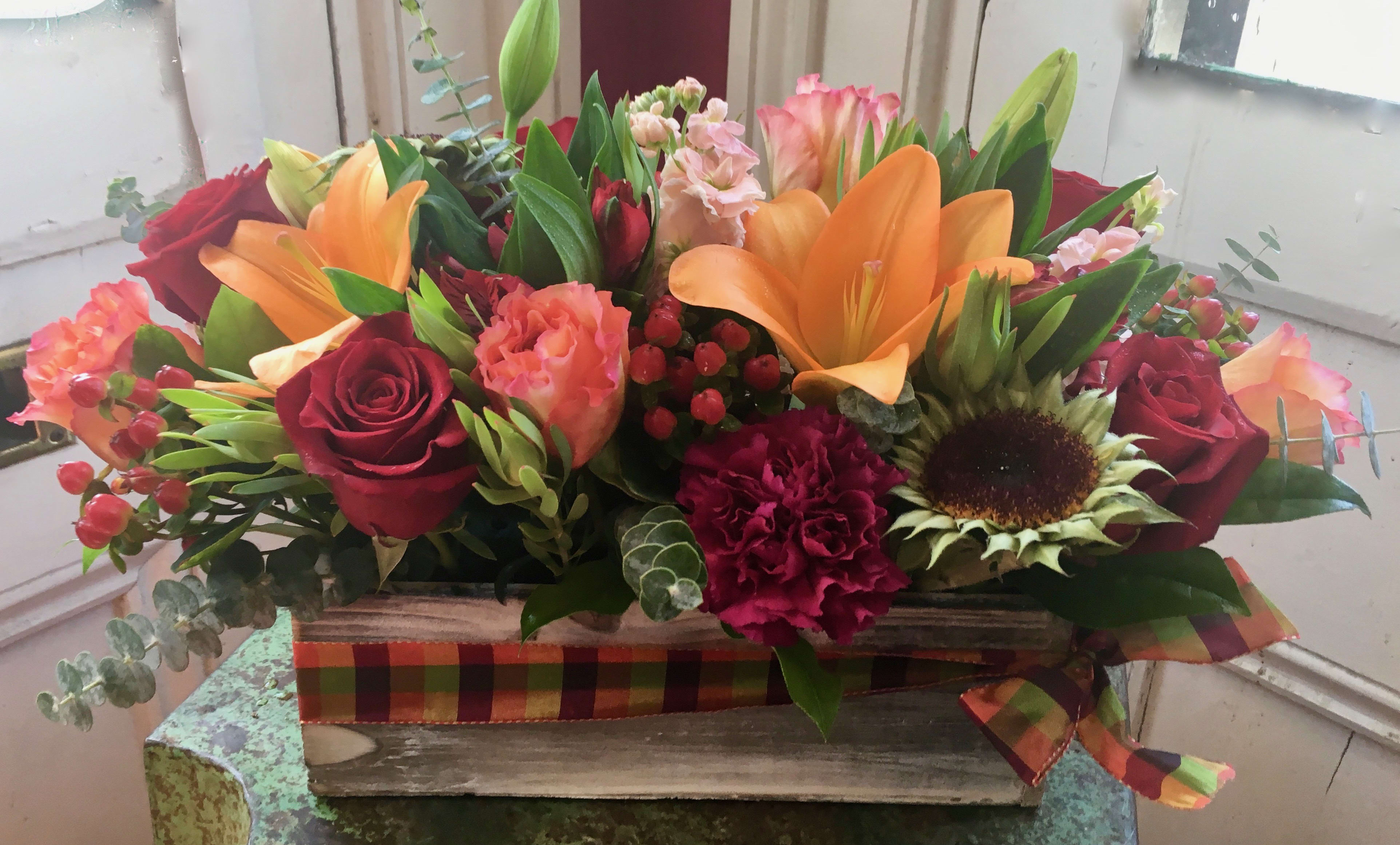 Mixed bouquet in a rustic wooden box with red roses and orange lilies