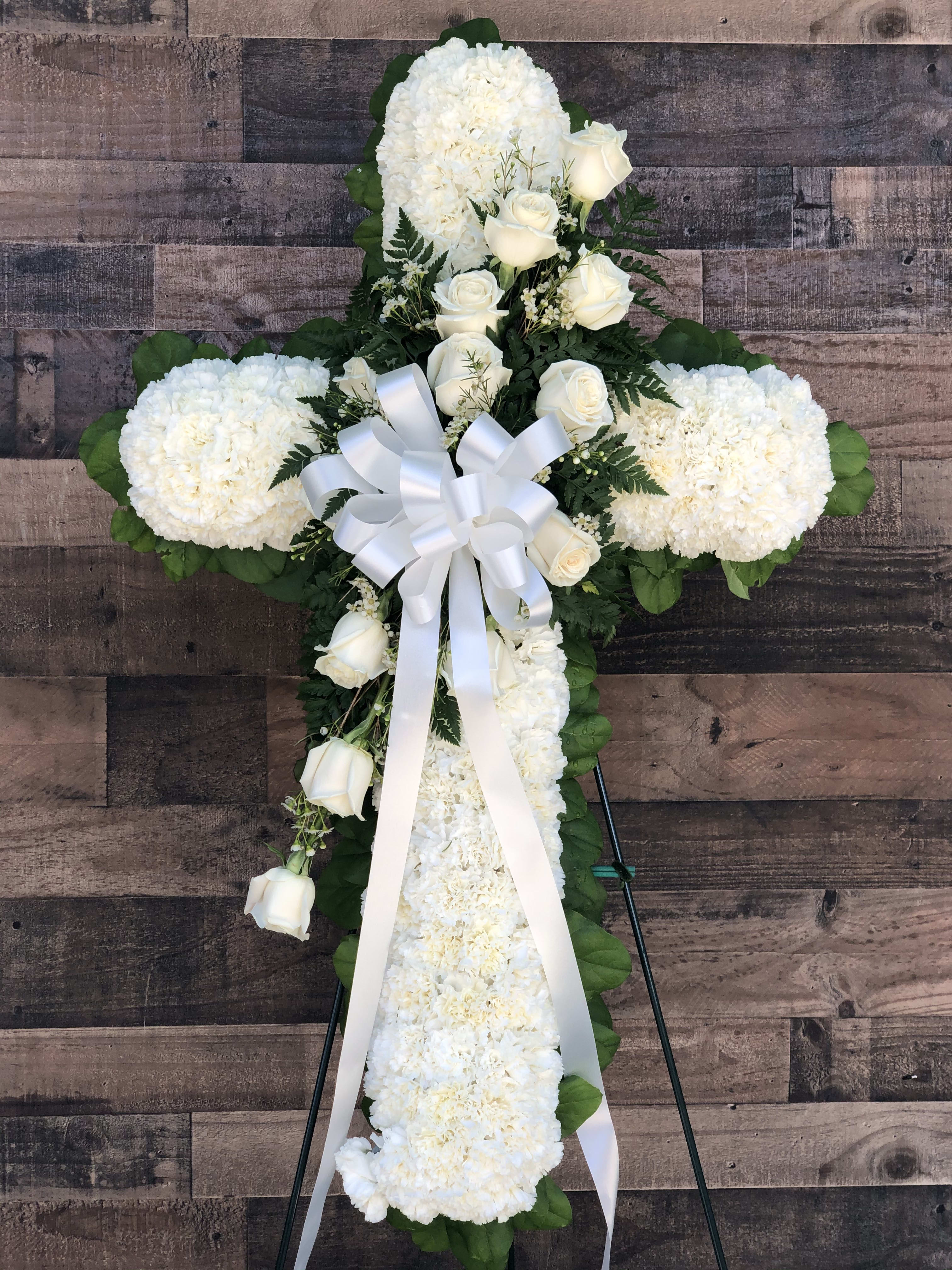 ELEGANT MEMORIES FUNERAL CROSS - An elegant funeral cross designed in all white, including roses, carnations and greens on a standing easel.
