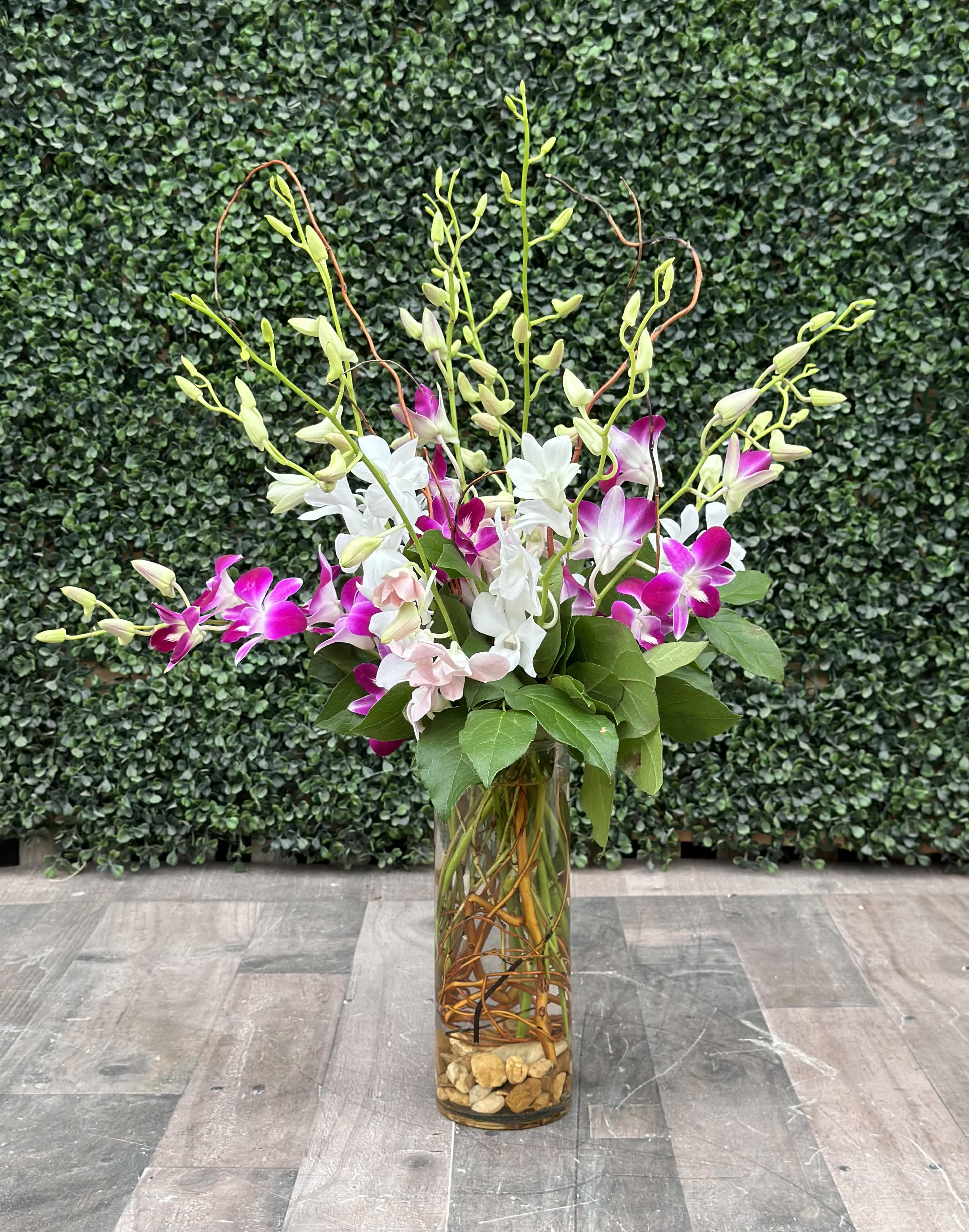 Tall orchid arrangement in a glass vase with pink and white blooms