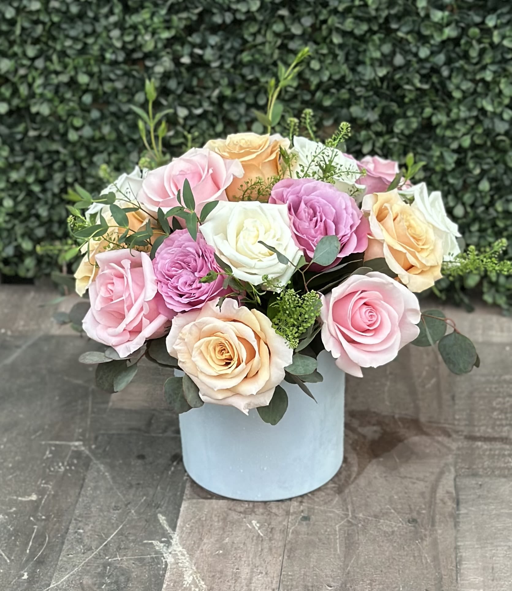 Pastel roses arranged in a light blue box with greenery