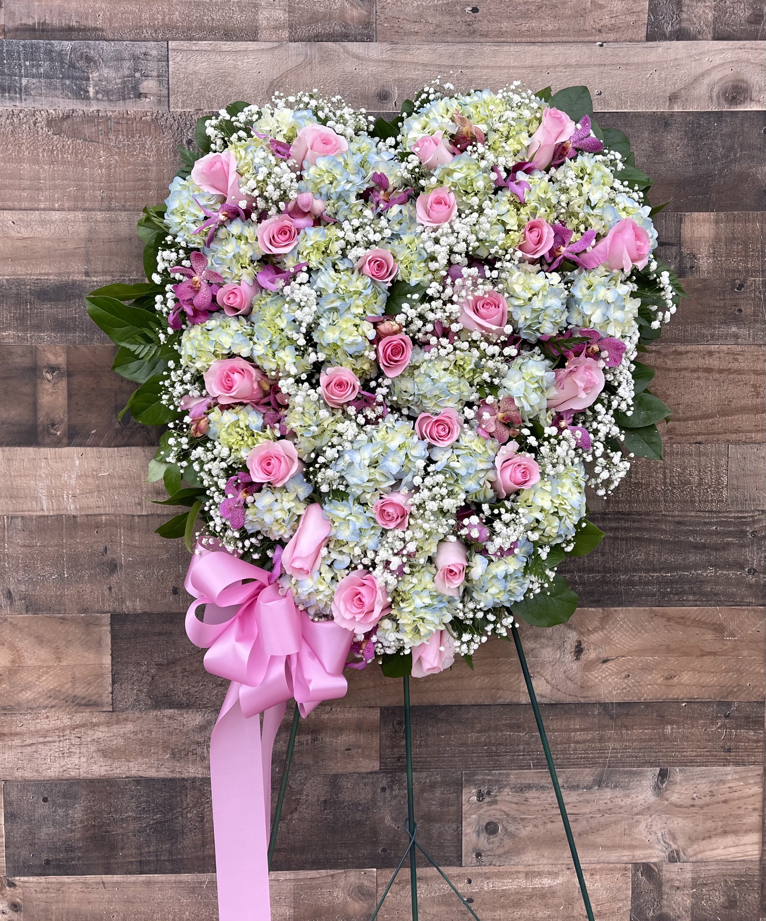 STANDING HEART SPRAY - SOLID HEART FILLED WITH AN ASSORTMENT OF PASTEL FLOWERS. WILL INCLUDE HYDRANGEAS AND ROSES ALONG WITH OTHER BEAUTIFUL FLOWERS. WE CAN CUSTOMIZE COLORS. CALL FOR MORE DETAILS