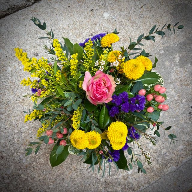 Love &amp; Huggs - A stunning arrangement featuring a white and pink-tipped rose, yellow pomp mums, purple status, pink berries with foliage accents. 