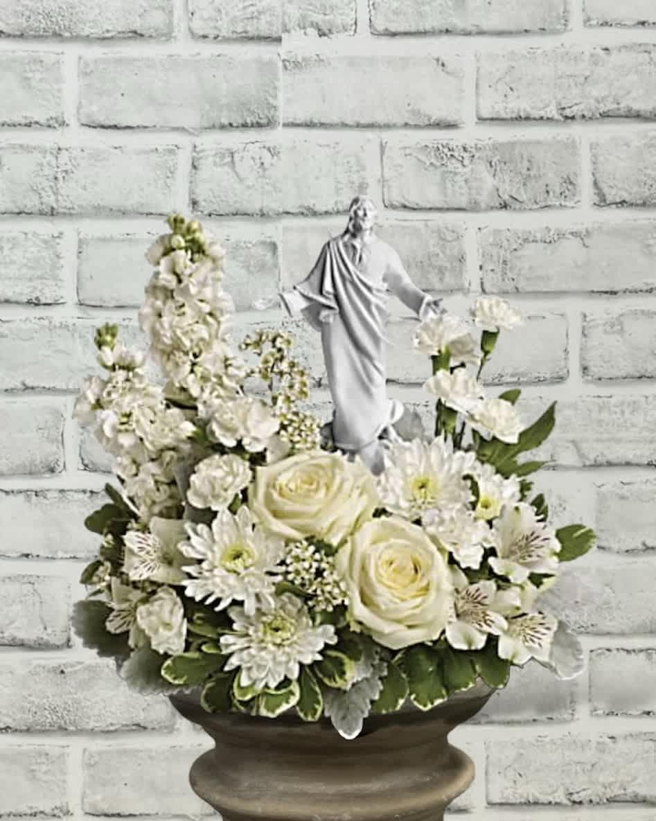White floral arrangement with a small religious statue in a pedestal bowl