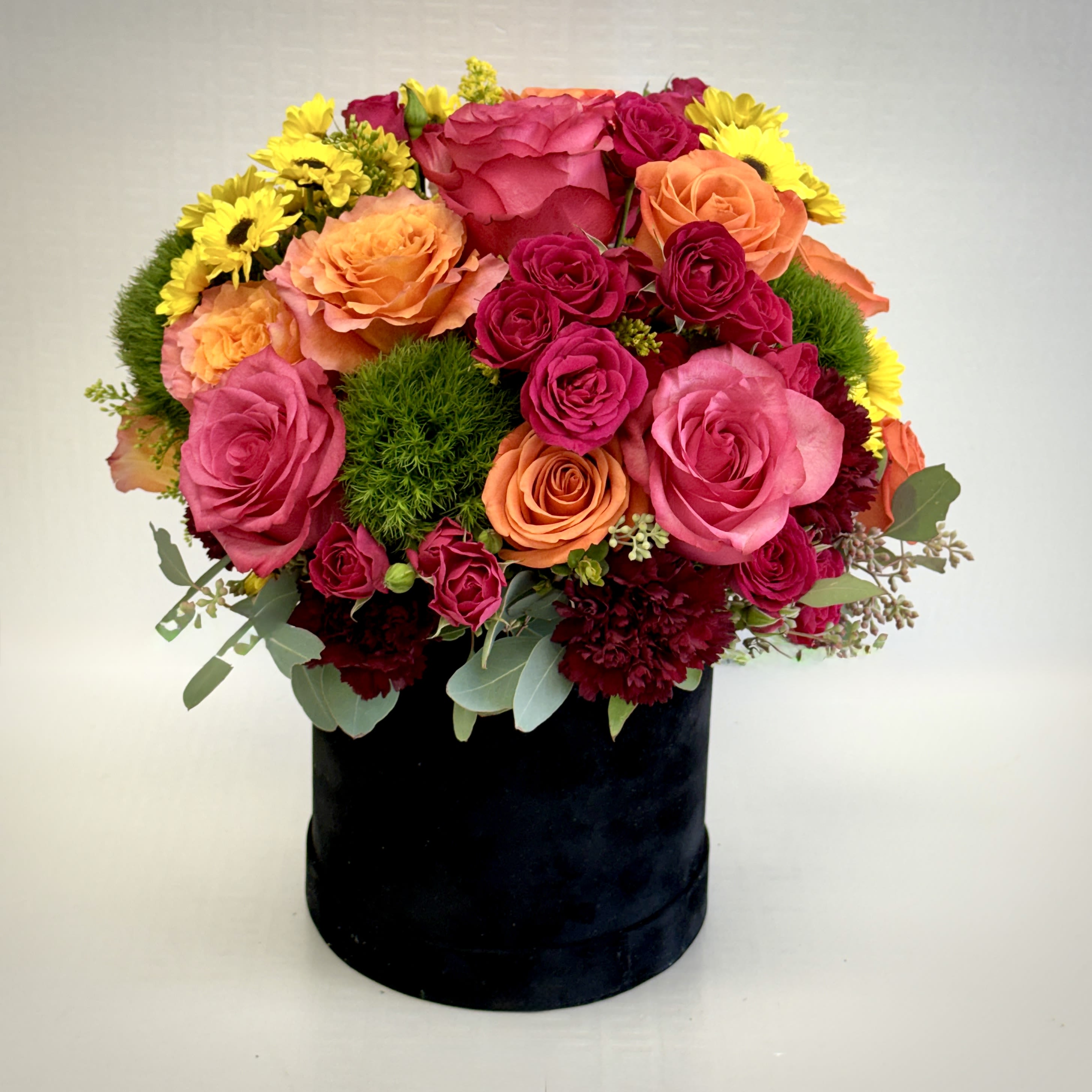 Sunset Bloom Bouquet - A bold and joyful floral design featuring vivid pink and orange roses, playful spray roses, and fresh seasonal blooms arranged in a modern black box for a stunning statement piece.
