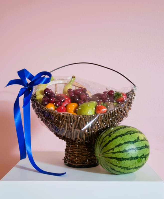 Summer Fruit Basket - Bursting with cheerful summer color, this Summer Fruit Basket is a fresh gift for birthdays, thank-yous, or to brighten someone's day. The woven basket arrangement reads like a thoughtful fruit bouquet-perfect as a casual get-well, hostess, or thinking-of-you gift that makes the recipient feel cared for and celebrated.  Ripe grapes, juicy strawberries, pears and an assortment of mixed fruit are artfully arranged to showcase green, red, purple and yellow hues. The harvest sits in a classic woven basket, wrapped in clear plastic for freshness and finished with a bright blue ribbon tied to the handle; a whole watermelon tucked in adds generous presence and a summery touch. The presentation is lively and approachable, offering both visual appeal and ready-to-eat goodness.  Give this to someone who loves fresh, wholesome treats-the kind of gift that says "enjoy today" and makes them feel thought of. Ready to deliver as shown, the basket arrives wrapped for protection; for best enjoyment, store refrigerated once unwrapped and consume fruit within a few days.