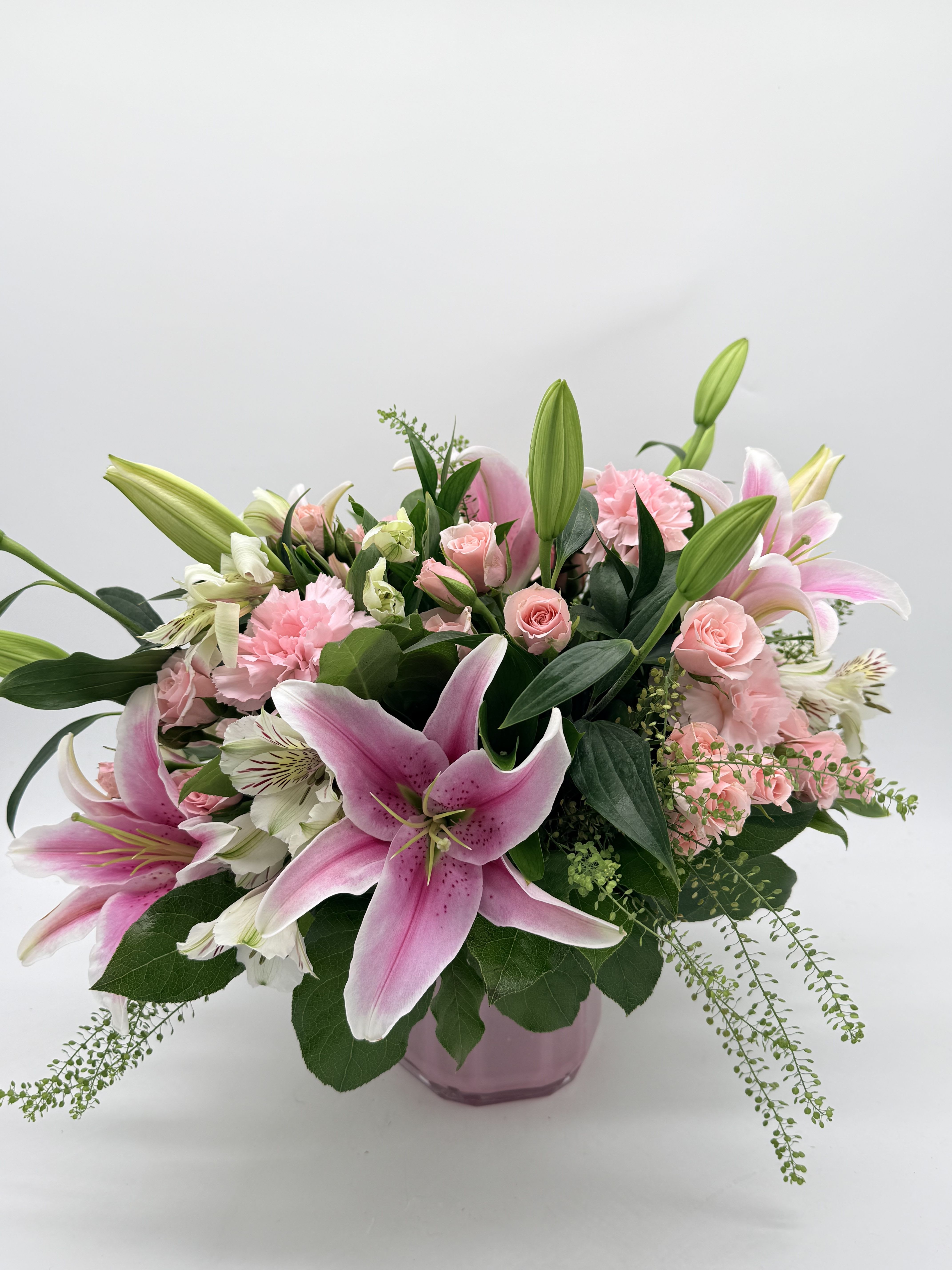 At the Ballet - Large pink lilies burst open above a cloud of soft pink roses, ruffled carnations, and delicate white alstroemeria-a romantic birthday bouquet or anniversary arrangement that reads as both joyful and tender. The bright, sculptural lily blooms create an immediate focal point so the person you're celebrating will feel truly seen, while the pastel palette and lush greenery keep the mood gentle enough for Mother's Day or a thoughtful get-well gift. Whether you're marking a milestone, saying "thinking of you," or brightening someone's recovery, this bouquet delivers an immediate sense of warmth and celebration.