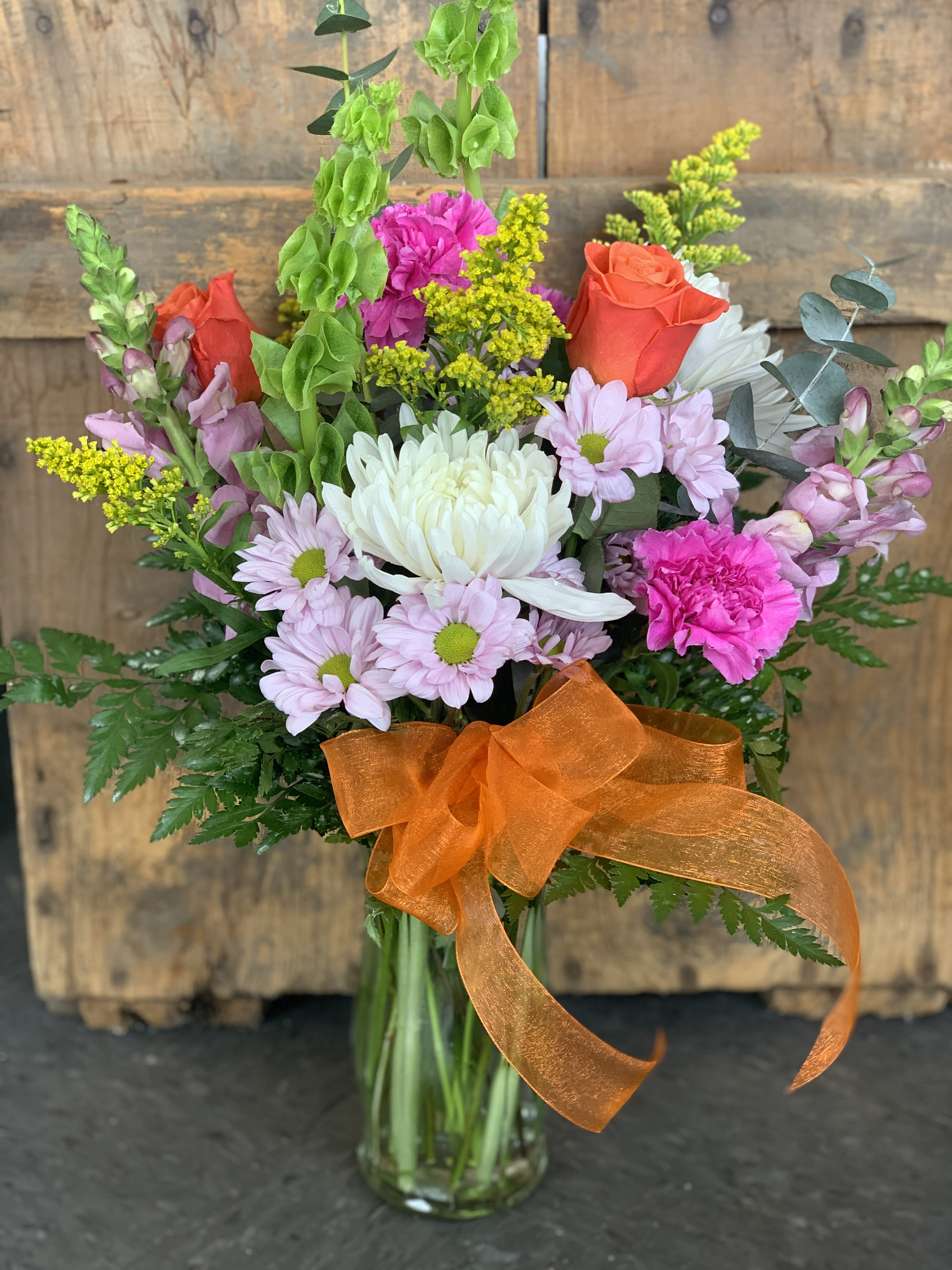 Mixed bouquet in a glass vase with orange ribbon