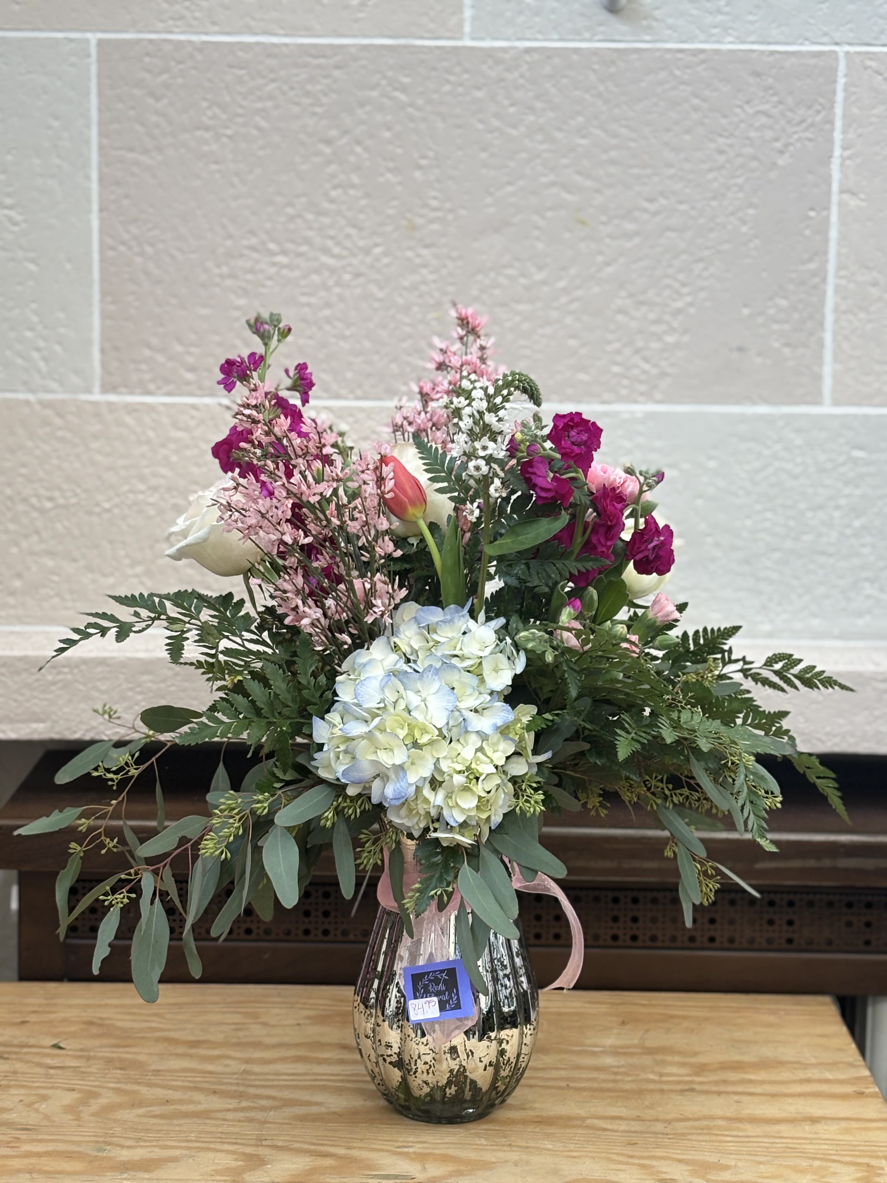 Mixed bouquet in a metallic vase with pink, white, and blue blooms