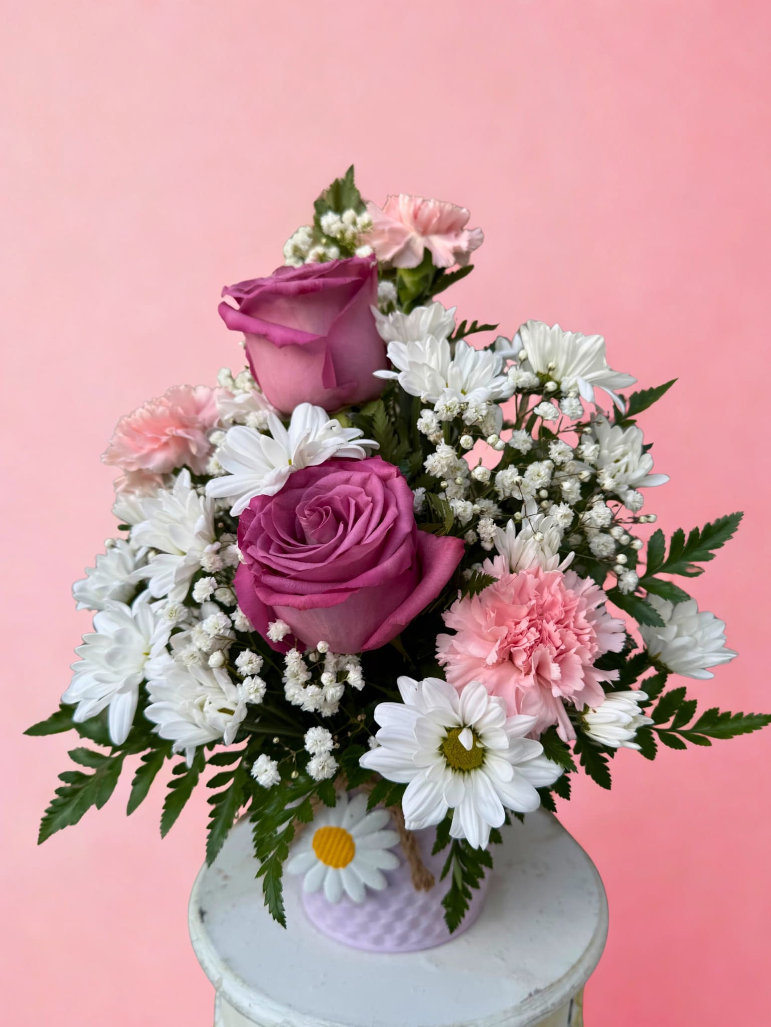 Pink and white bouquet with roses, daisies, and carnations in a small vase