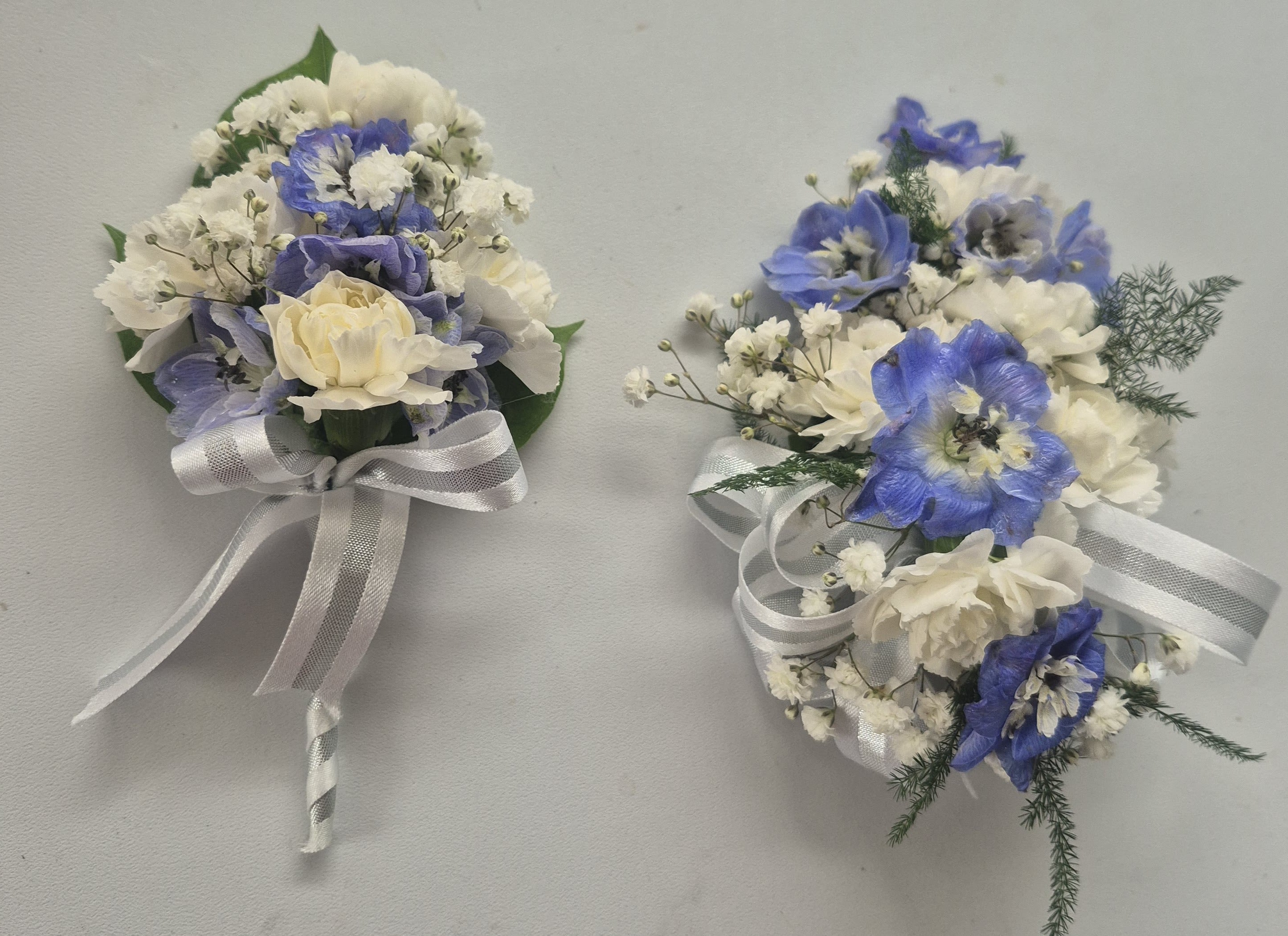 Two small wedding bouquets with blue and white flowers tied with white ribbon