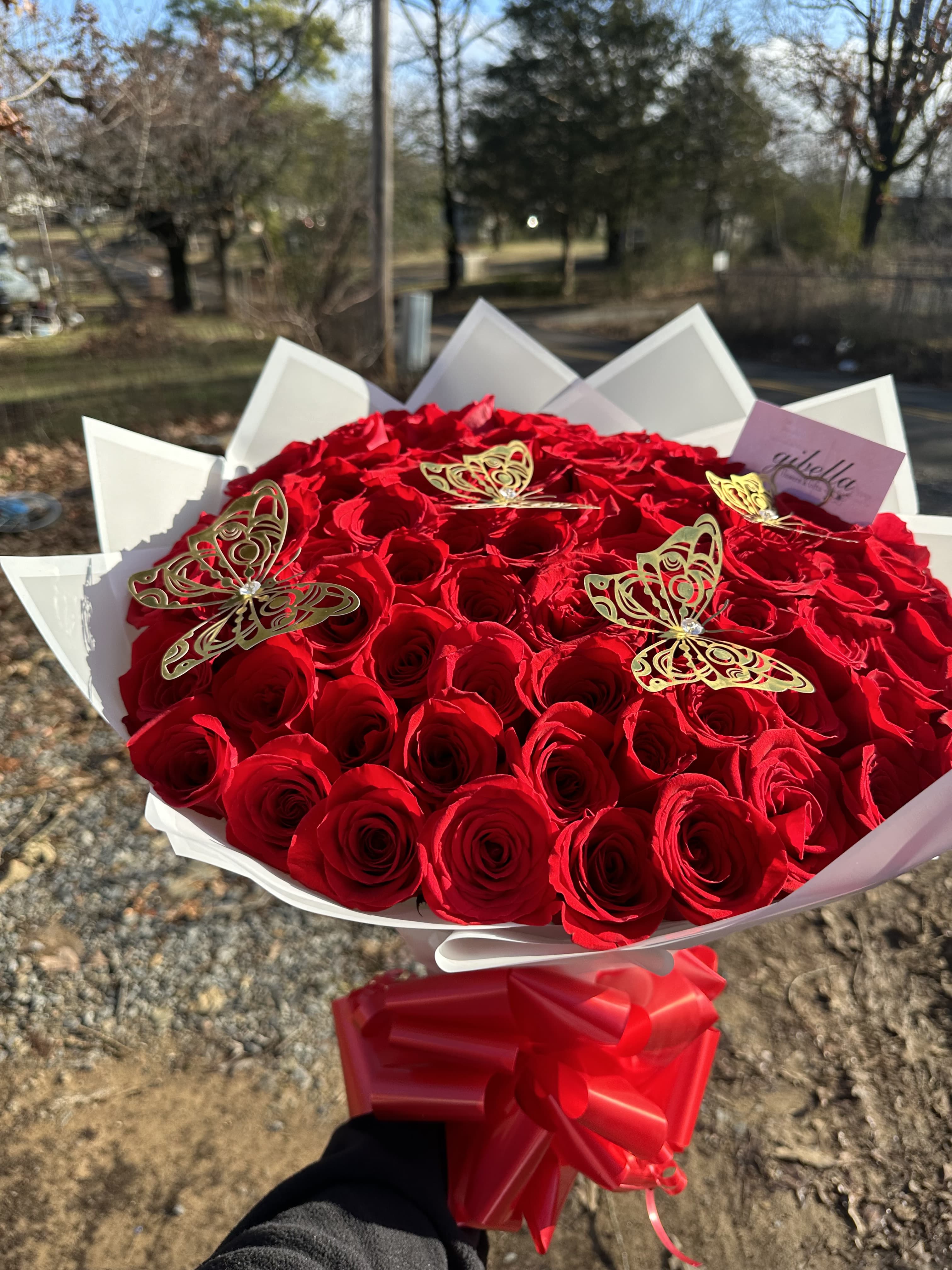 Large bouquet of red roses with gold butterfly accents and a red ribbon