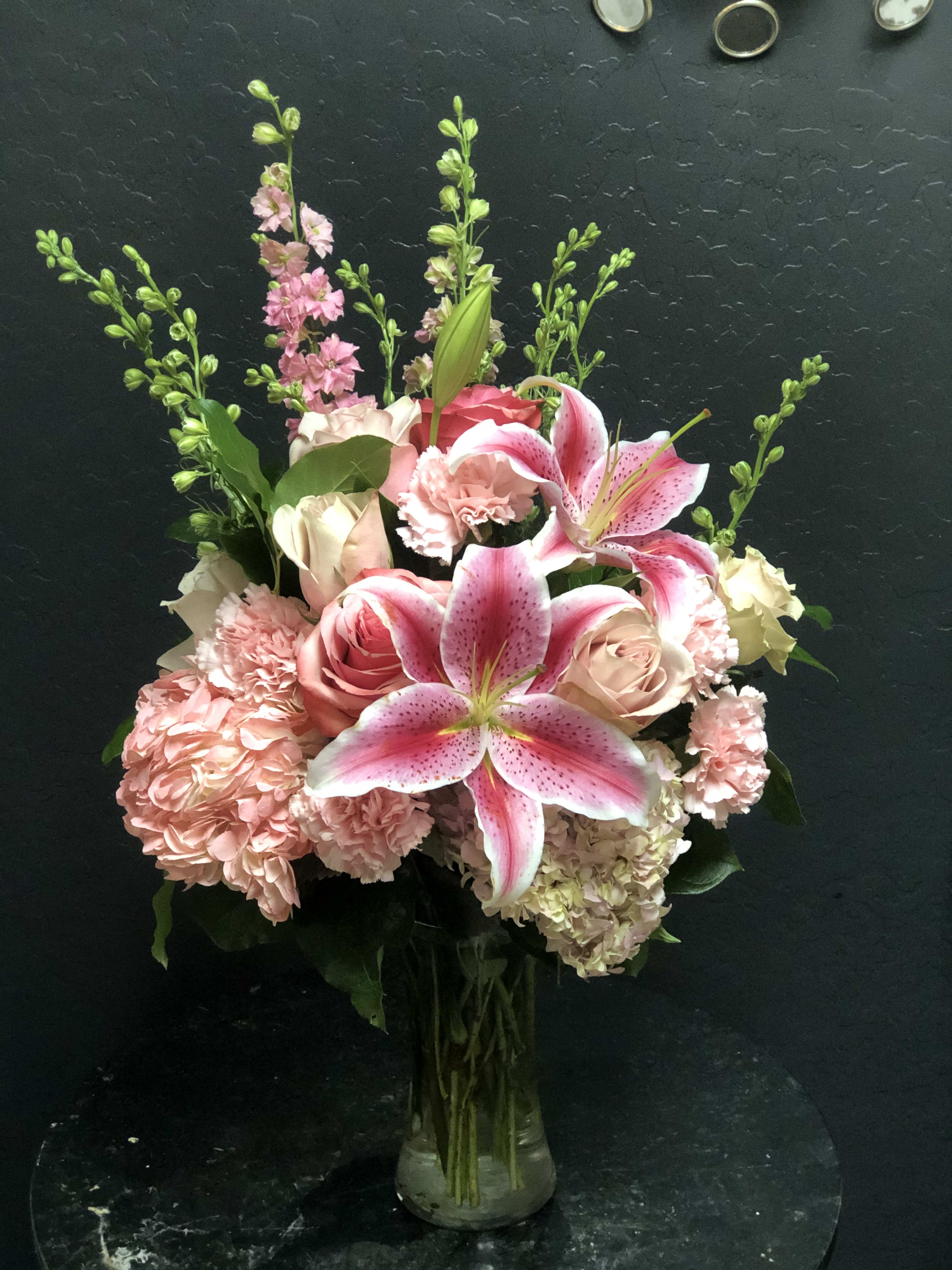 Wishes &amp; Blessings Bouquet - Wishes &amp; Blessing Bouquet is a stunning way to offer your condolences for their loss and commemorate the life of the deceased. Soft pink roses spray roses Oriental lilies hydrangea and larkspur are brought together in a clear glass vase to create an eye-catching display of soft serenity.