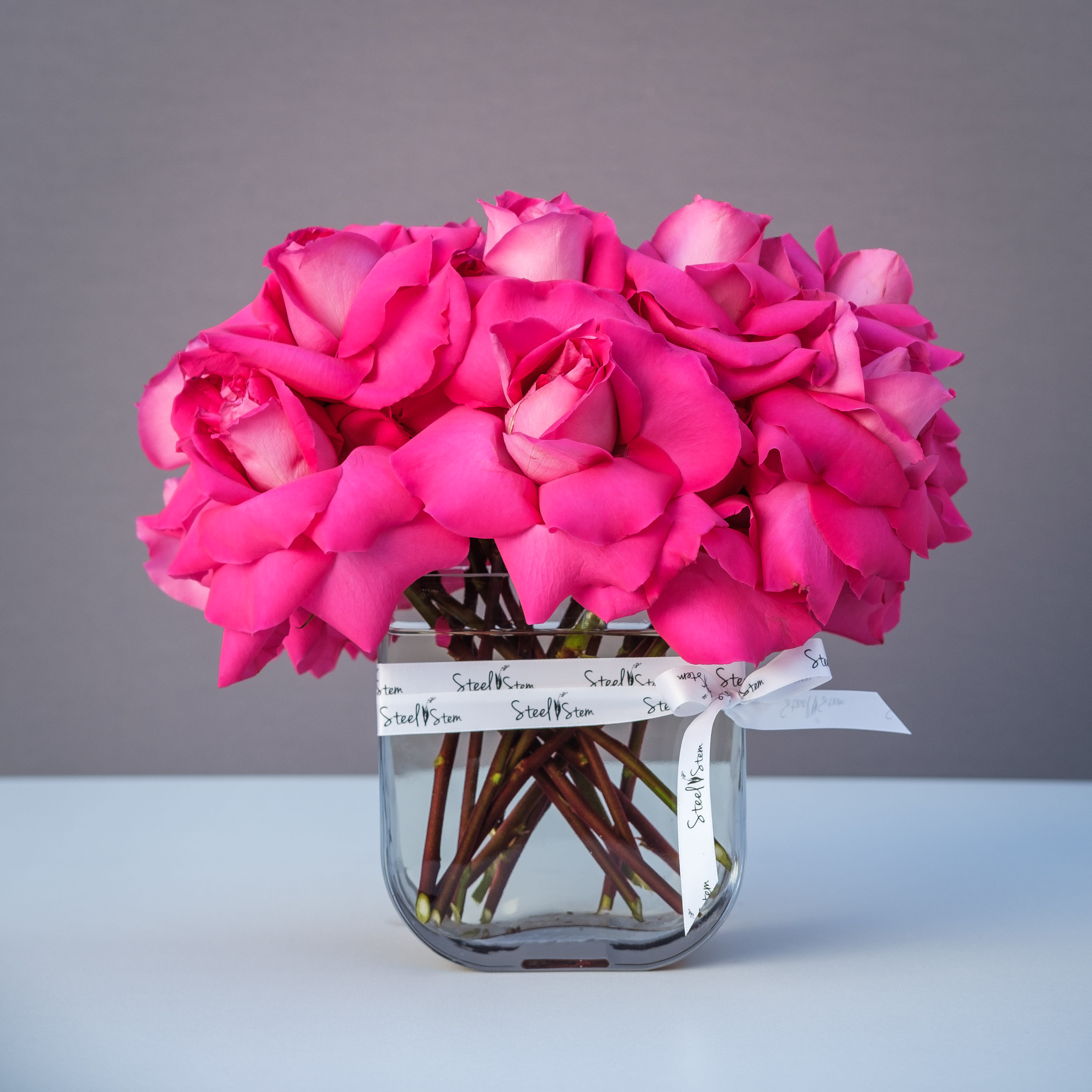 Sold Out Hottie - Chic &amp; feminine, enjoy a beautiful display of premium hot pink roses that are hand reflexed into a contemporary glass rectangular vase with our signature Steel Stem ribbon for an opulent finish.  A stunning gift to send to a love one, special friend, or to celebrate the birth of a new baby girl!