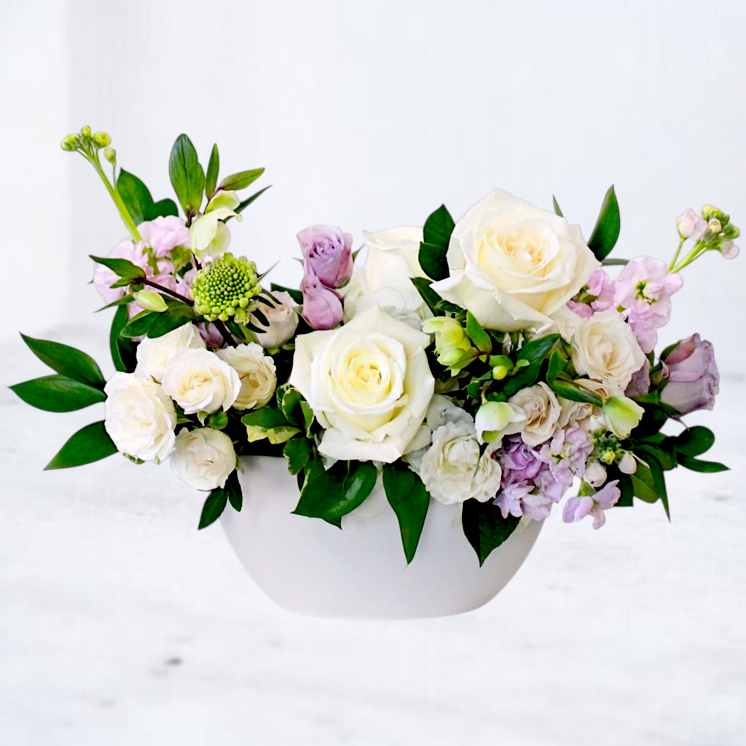 White and blush rose arrangement in a white bowl vase