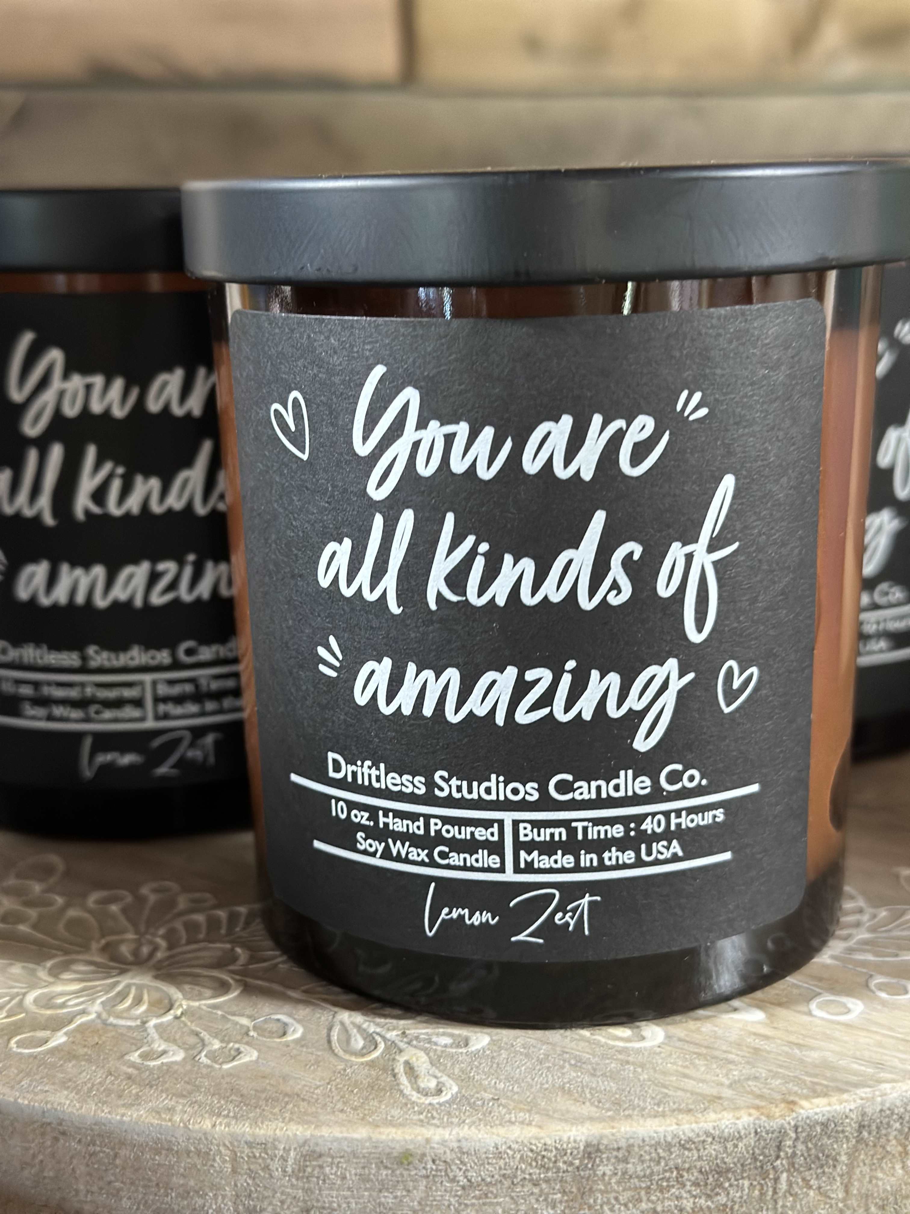 Black jar candle with a label reading "You are all kinds of amazing"