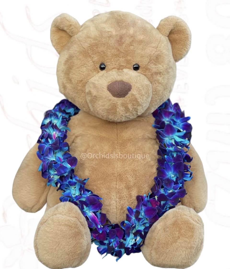 Tan teddy bear wearing a blue and purple flower lei