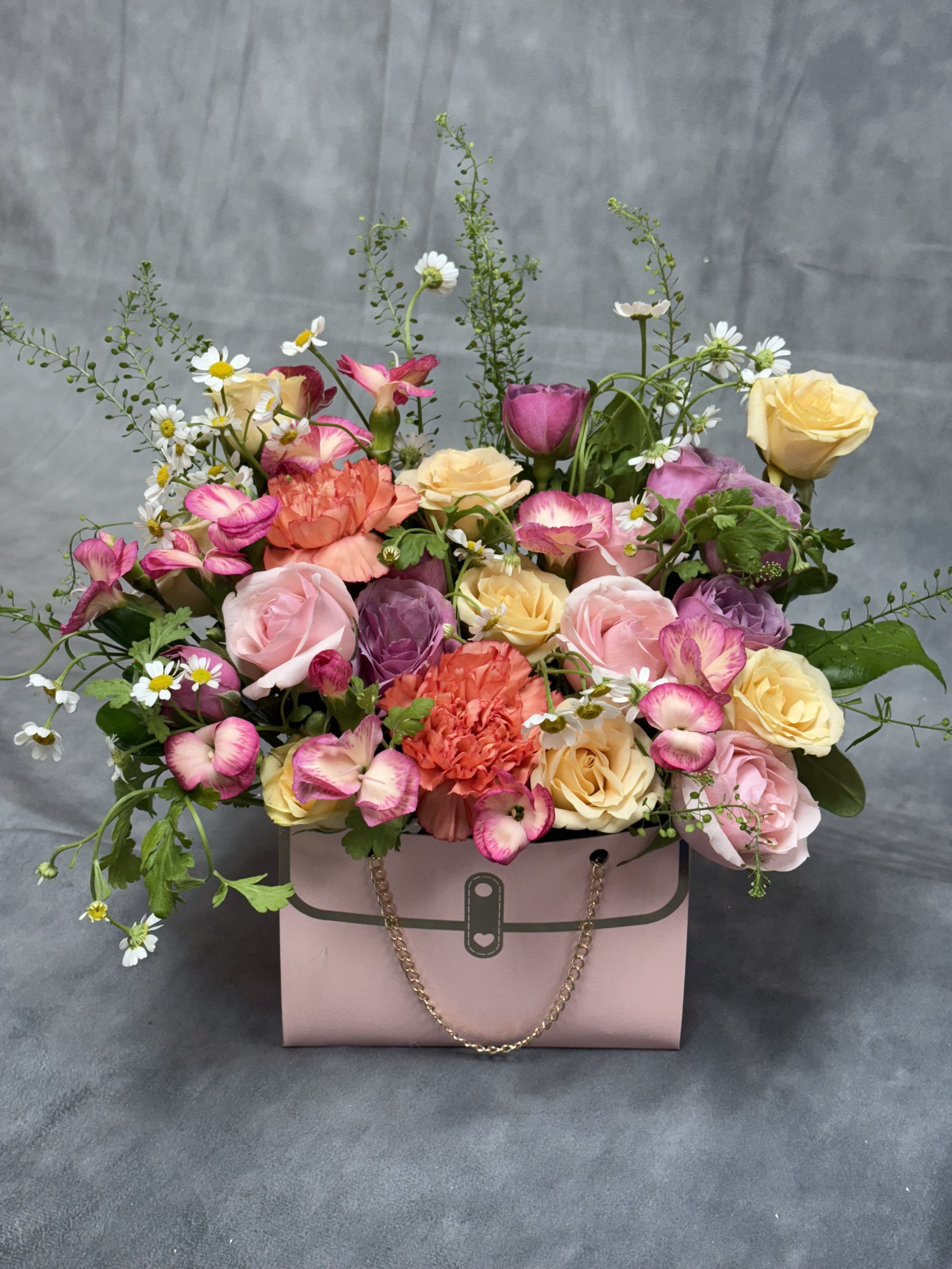 Pink gift box filled with roses, carnations, and daisies