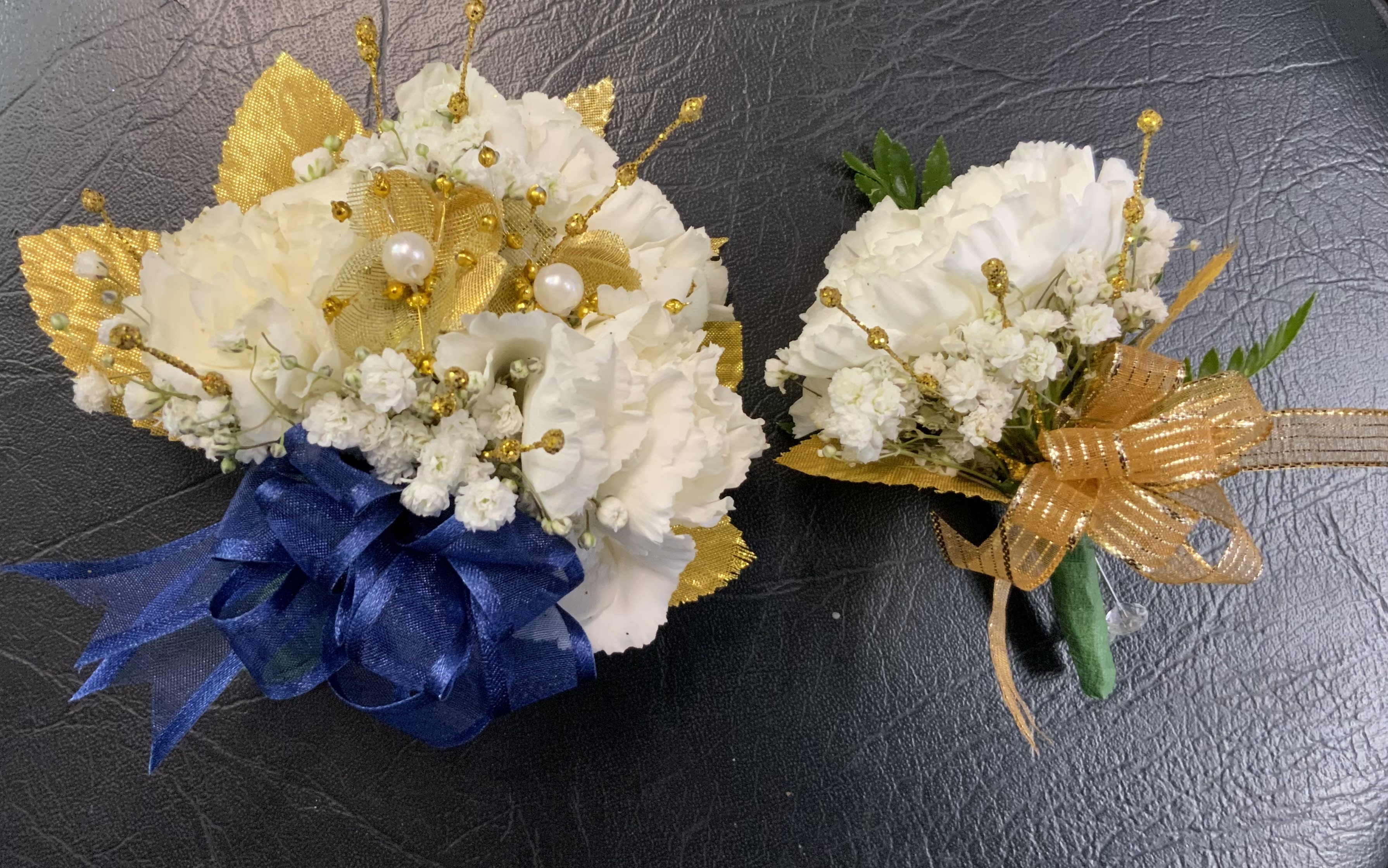 Two small white floral bouquets with gold accents and ribbon bows
