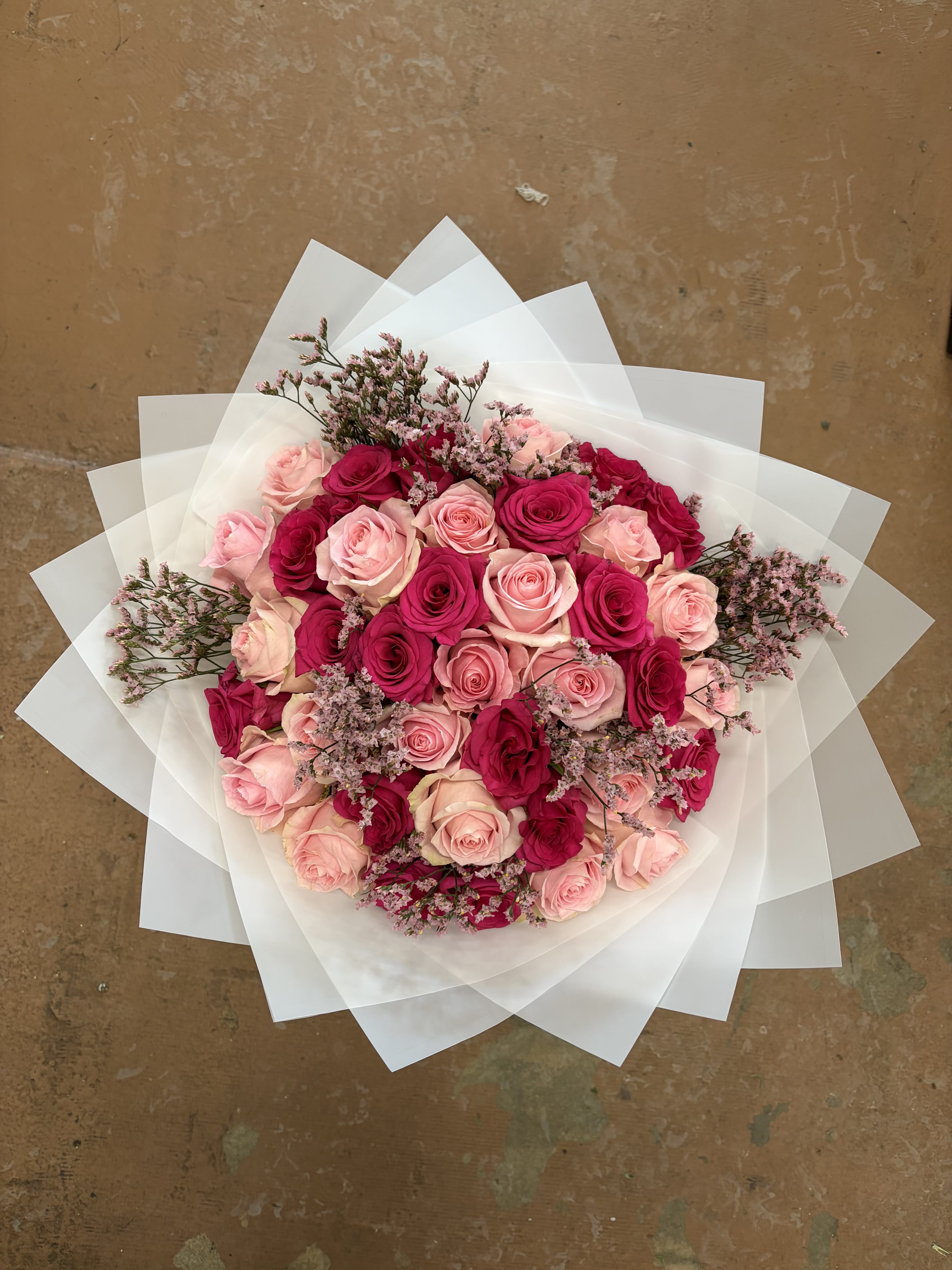 Bouquet of pink and hot pink roses wrapped in white paper