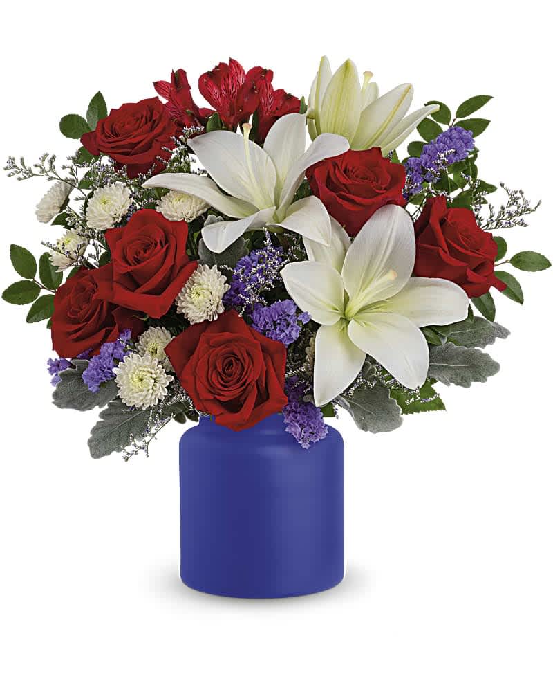 Rose Revelry Bouquet - Revel in the crisp, classic color scheme of pristine white lilies and radiant red roses, presented in a cobalt-hued, frosted glass jar. White asiatic lilies, red roses, red alstroemeria, white button spray chrysanthemums, purple sinuata statice and misty blue limonium are accented with dusty miller and huckleberry. Delivered in the Savannah Jar.