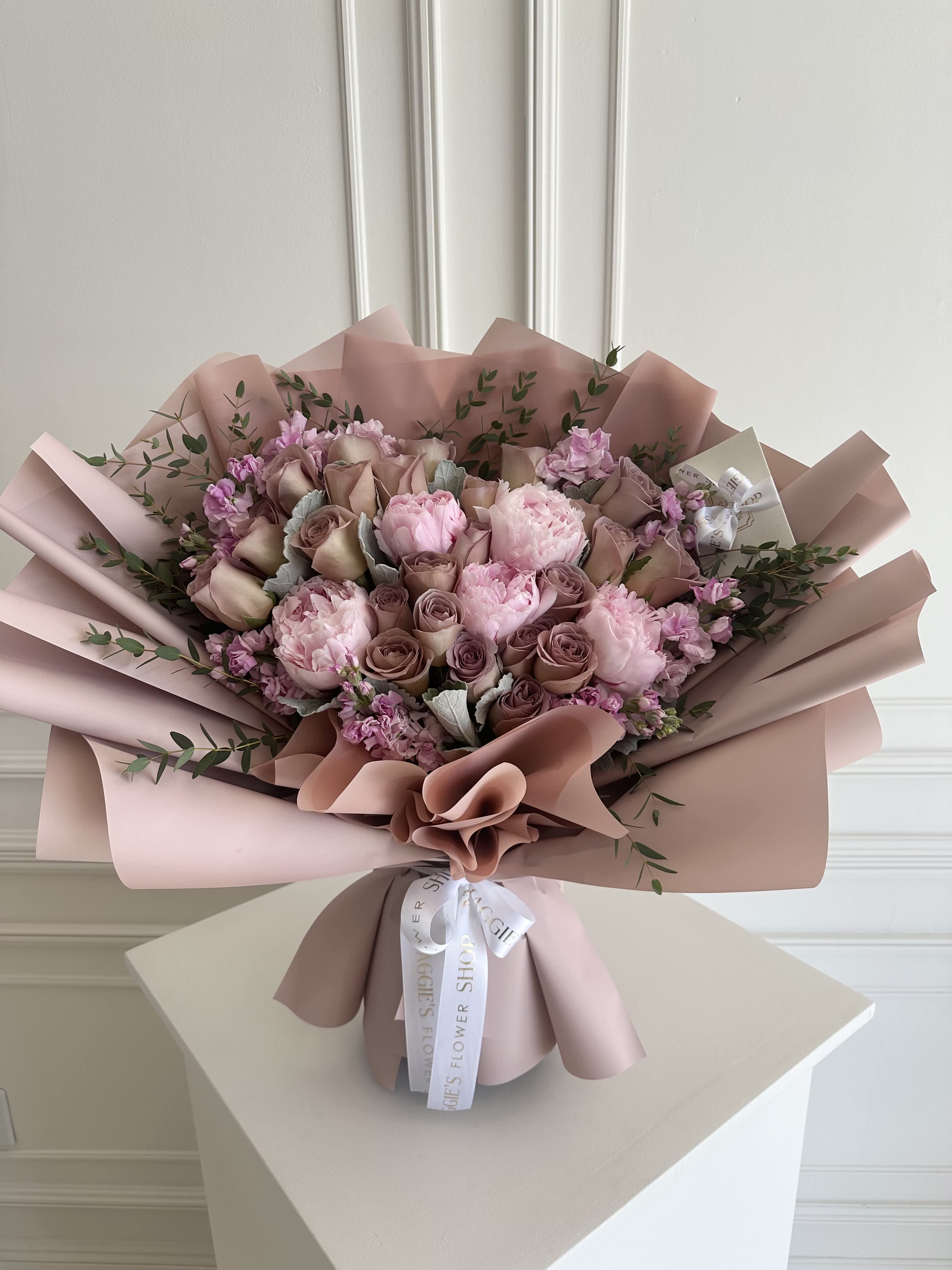 Pink and mauve bouquet of roses and peonies wrapped in blush paper