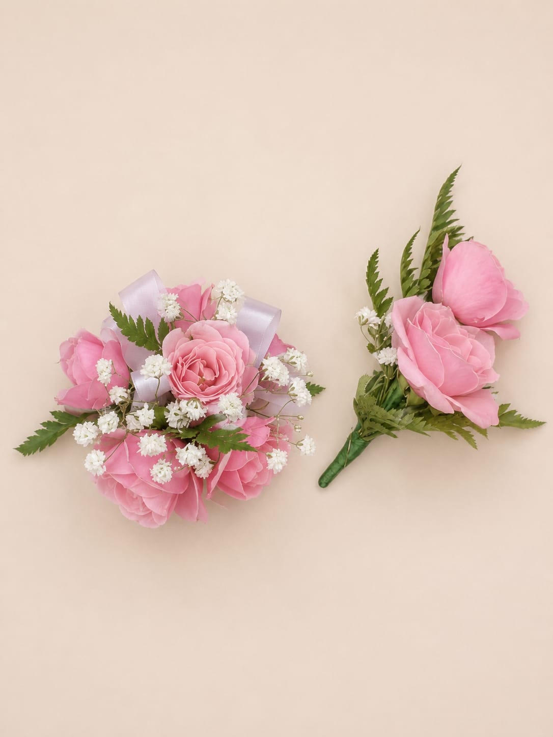 Prom Set Corsage Pink - Soft pink roses arranged in a compact, rounded corsage set create a quietly romantic accent for weddings or prom. This flower arrangement and matching boutonniere read formal and coordinated-perfect for the bride, bridesmaids, or the person you're celebrating-bringing a gentle blush of pink with white and pale lavender highlights that will make them feel cherished.  