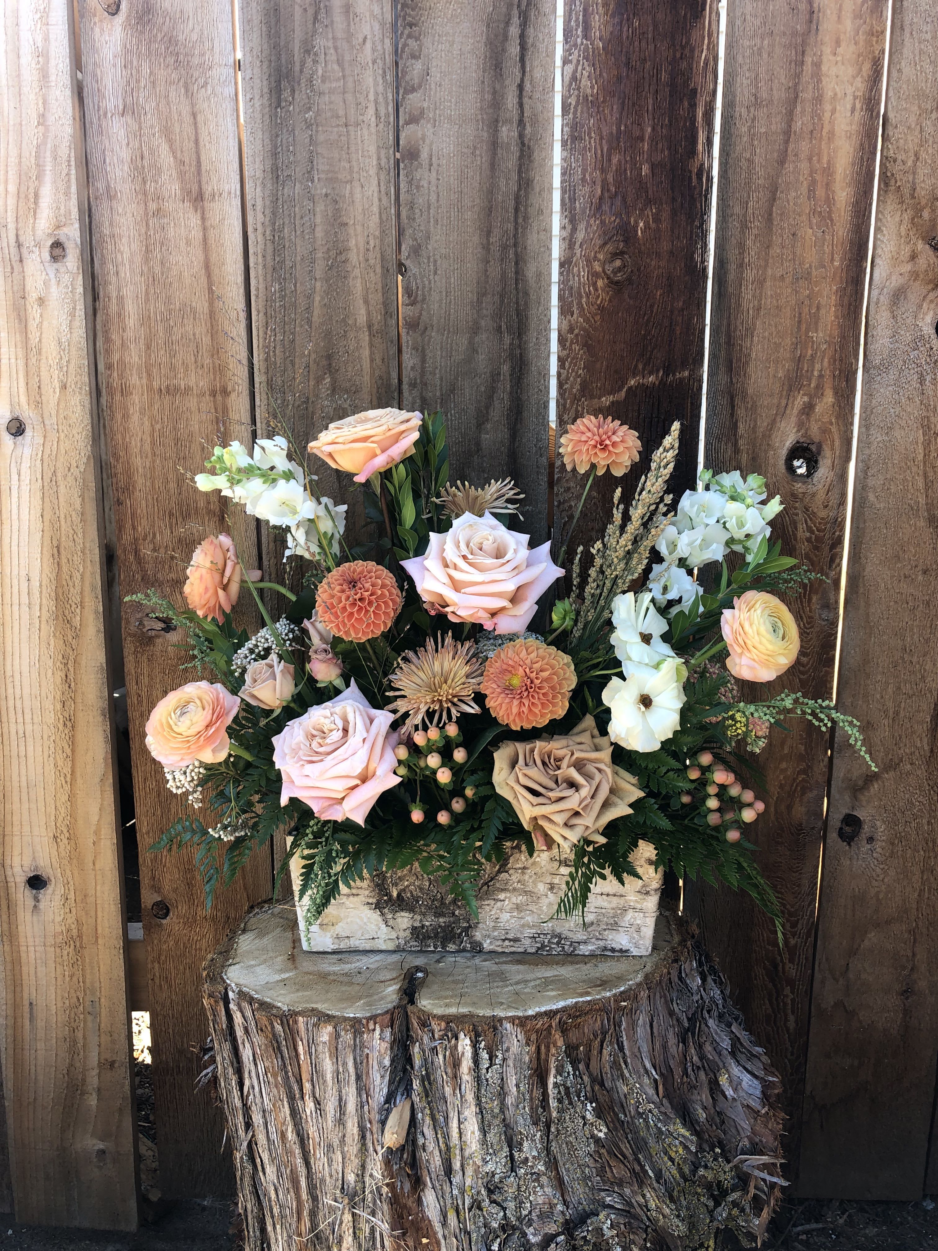 Peach and blush roses with dahlias and ranunculus in a rustic wooden box centerpiece