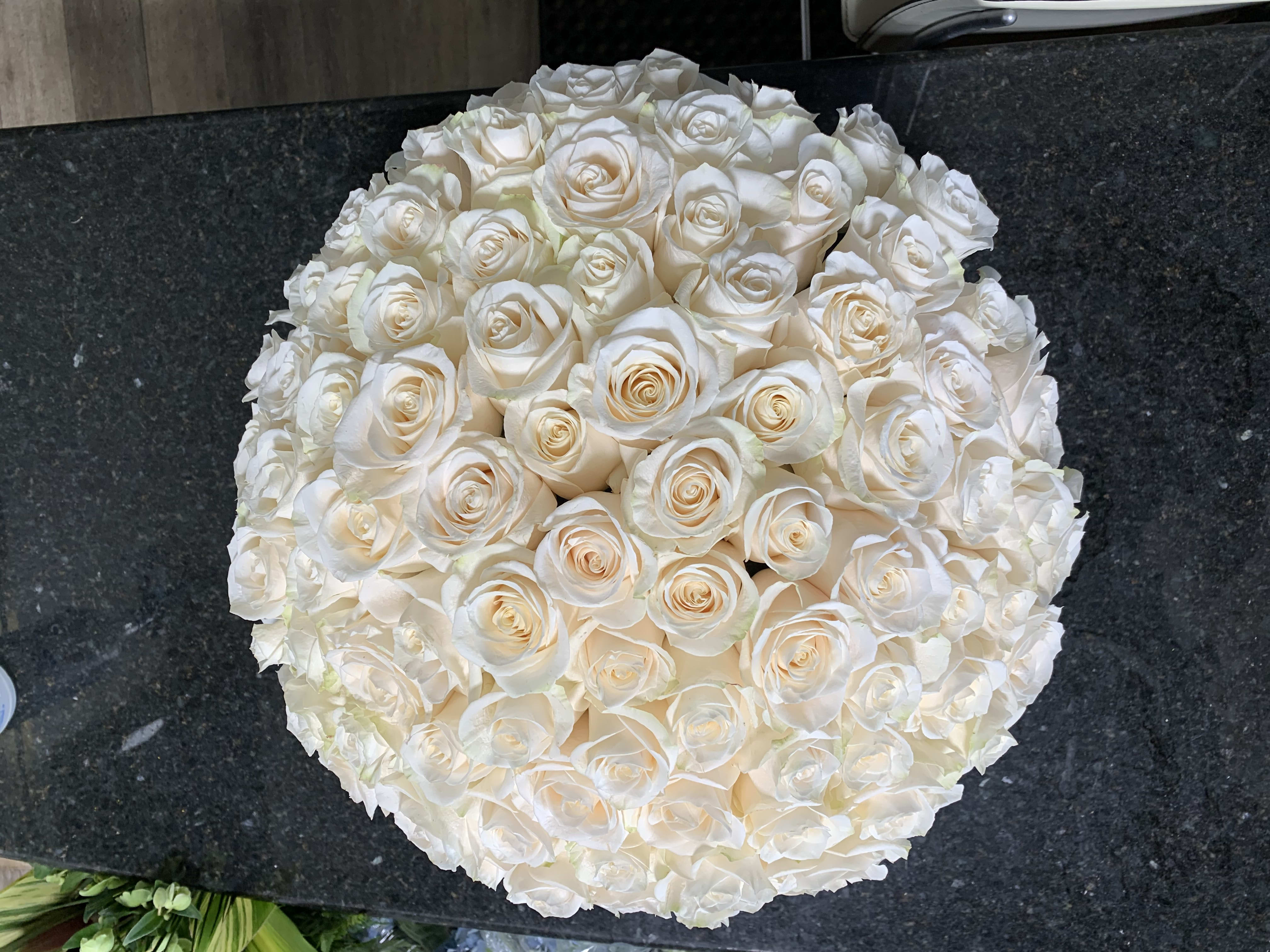 Round bouquet of white roses with a few cream-tinted blooms