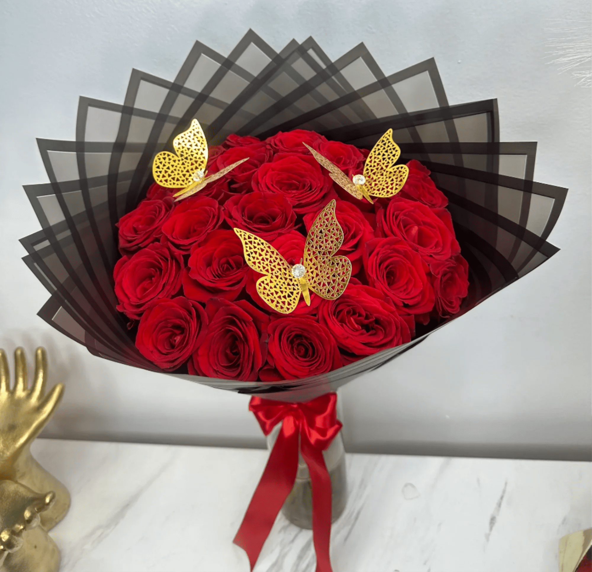 Bouquet of red roses wrapped in black paper with gold butterfly accents