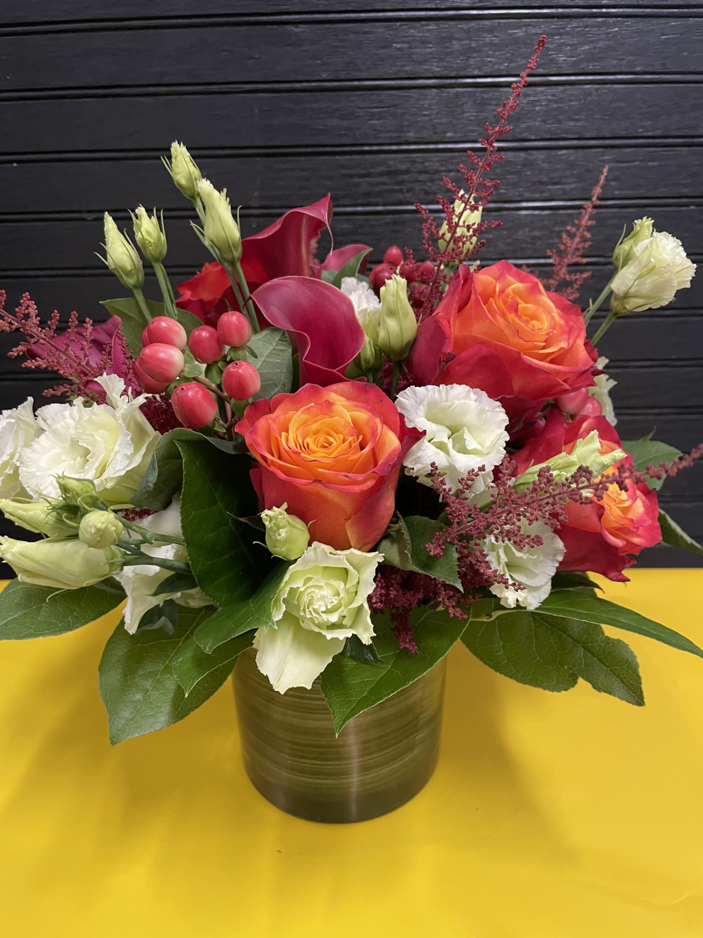 Bouquet of orange roses and white lisianthus in a gold vase